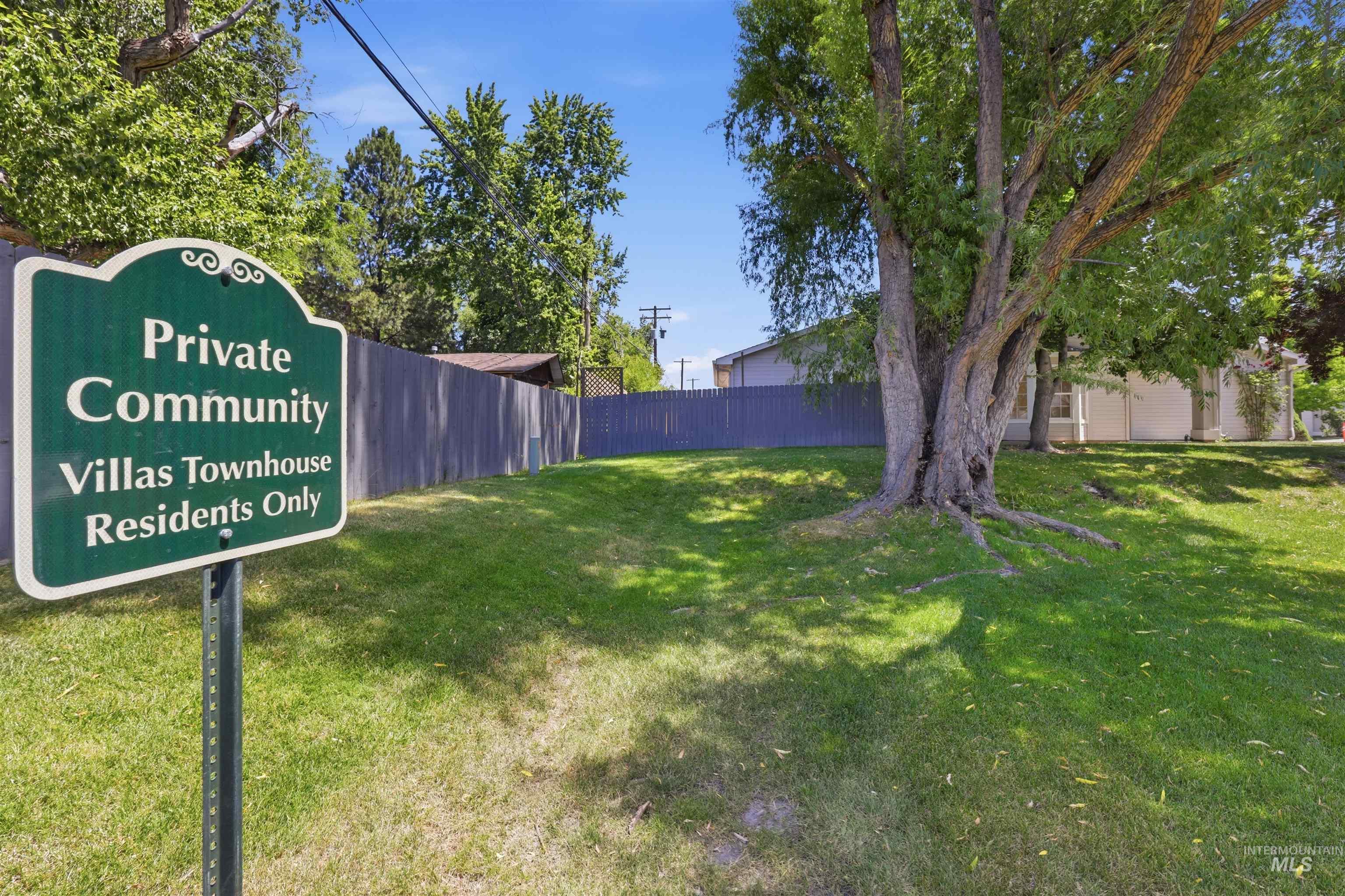 Green sign indicating "Private Community Villas Townhouse Residents Only" set within a grassy area