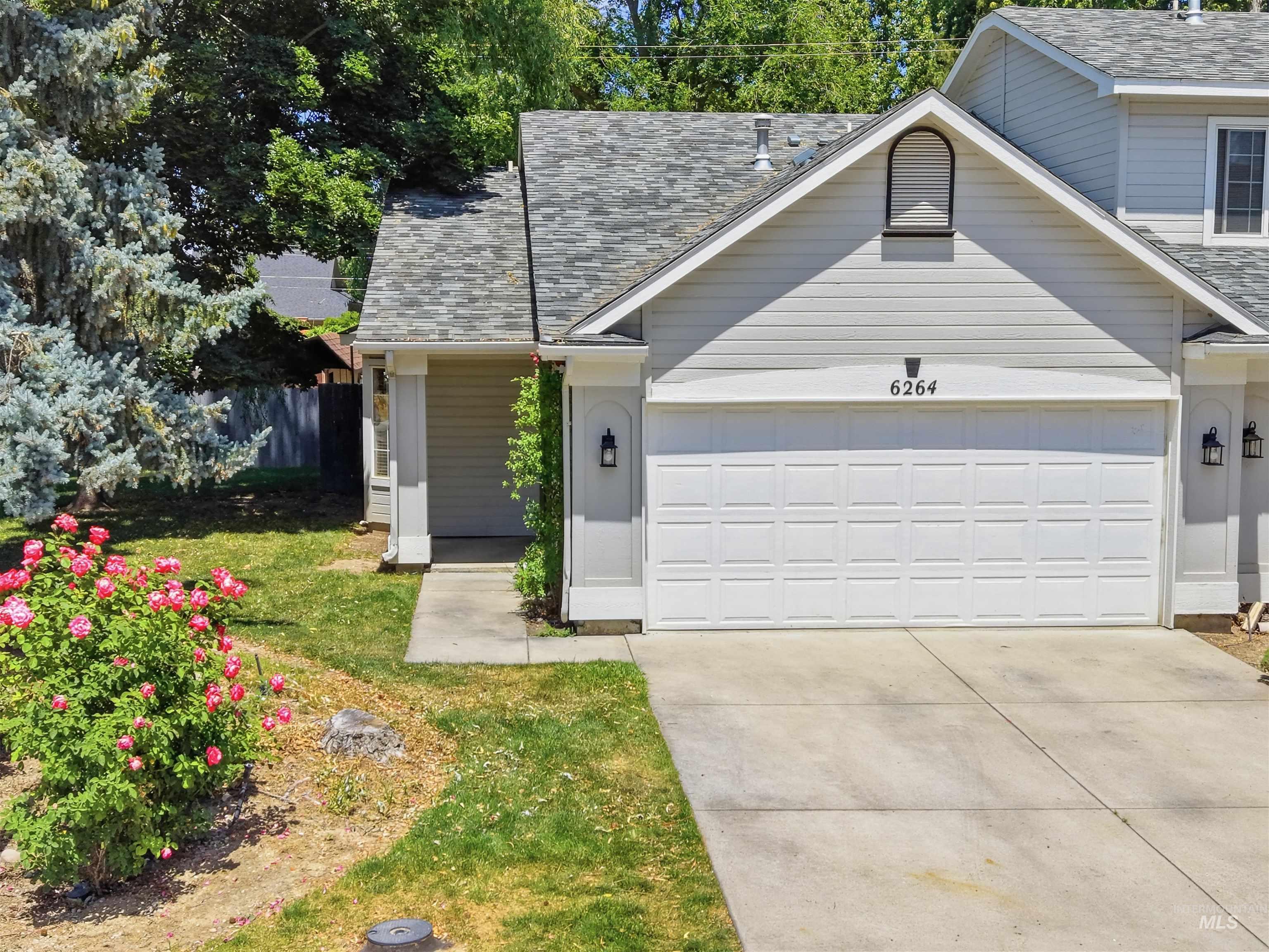 Light gray siding exterior with a paneled garage door and a gabled roofline