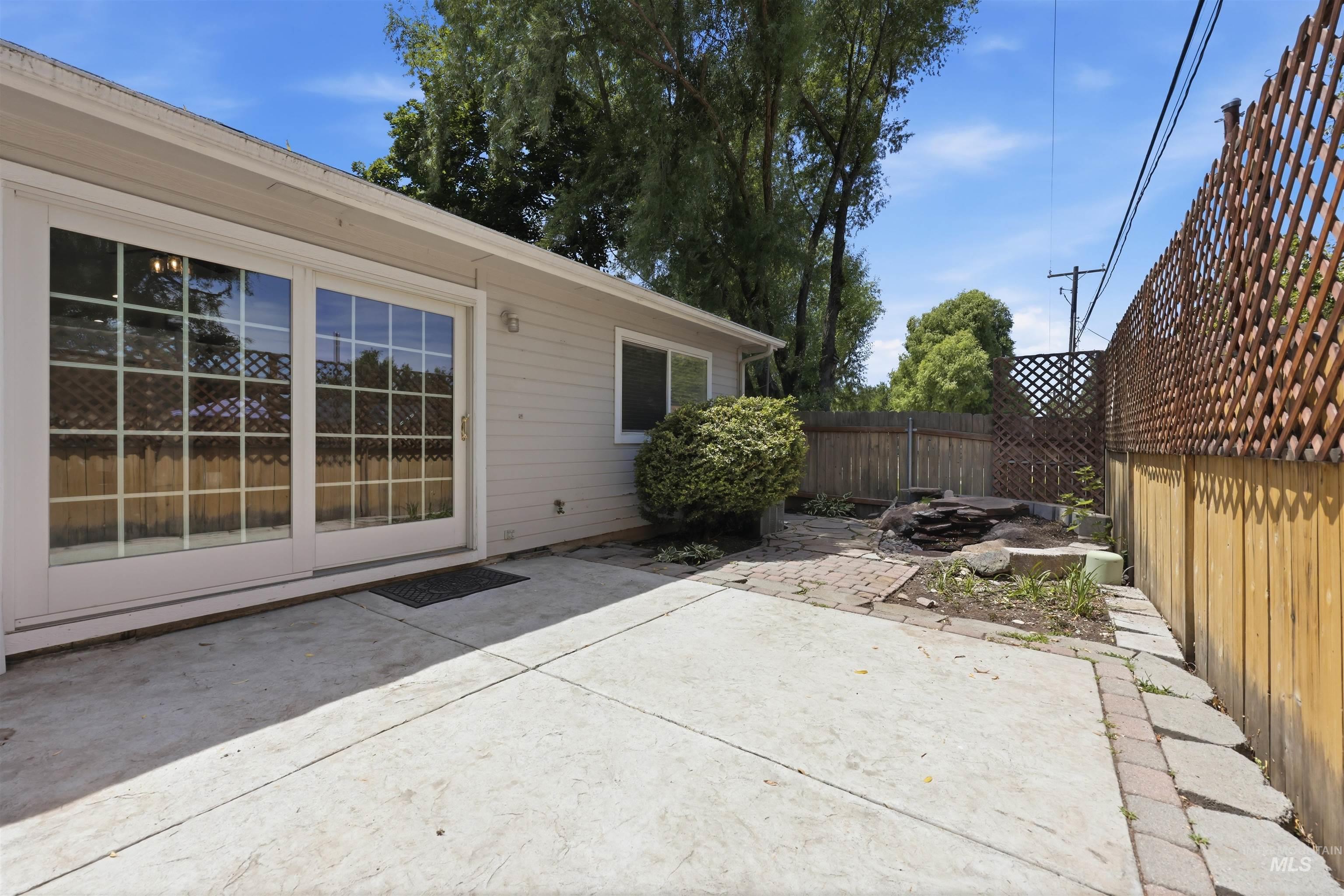 Concrete patio with sliding glass doors, a wood fence, and a decorative lattice privacy screen