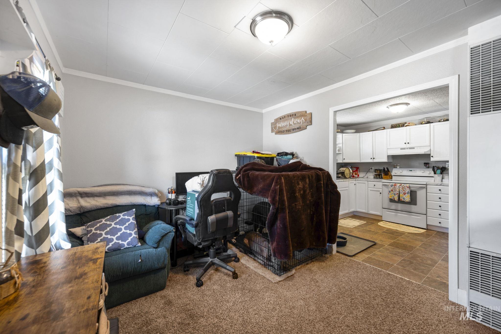 Office area featuring dark carpet, a heating unit, and crown molding