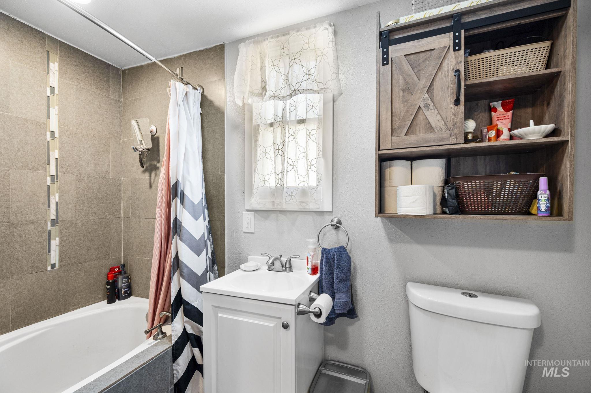 Bathroom featuring tiled shower / bath, vanity, and a textured wall