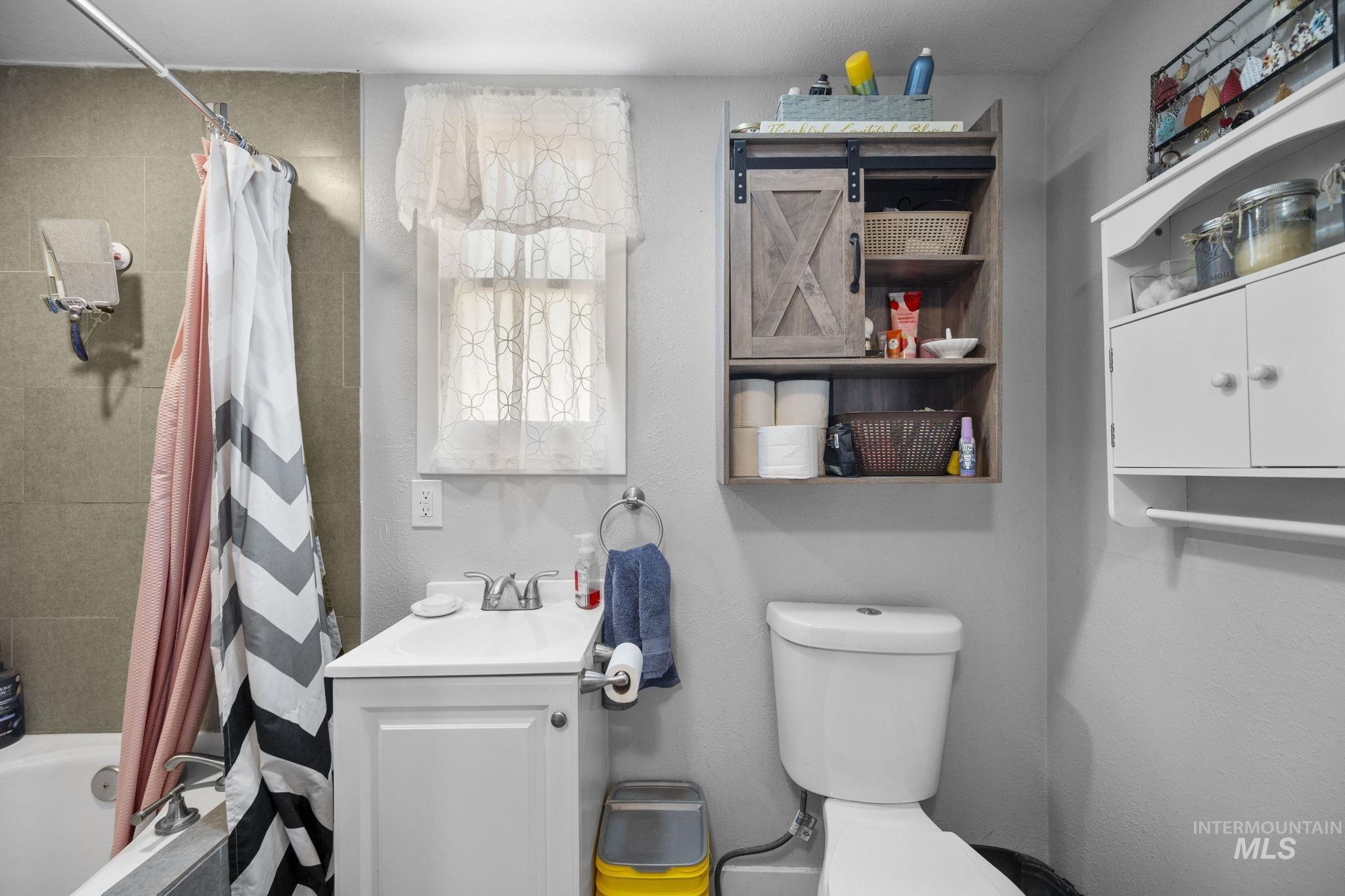 Full bathroom with tiled shower / bath, vanity, and a textured wall
