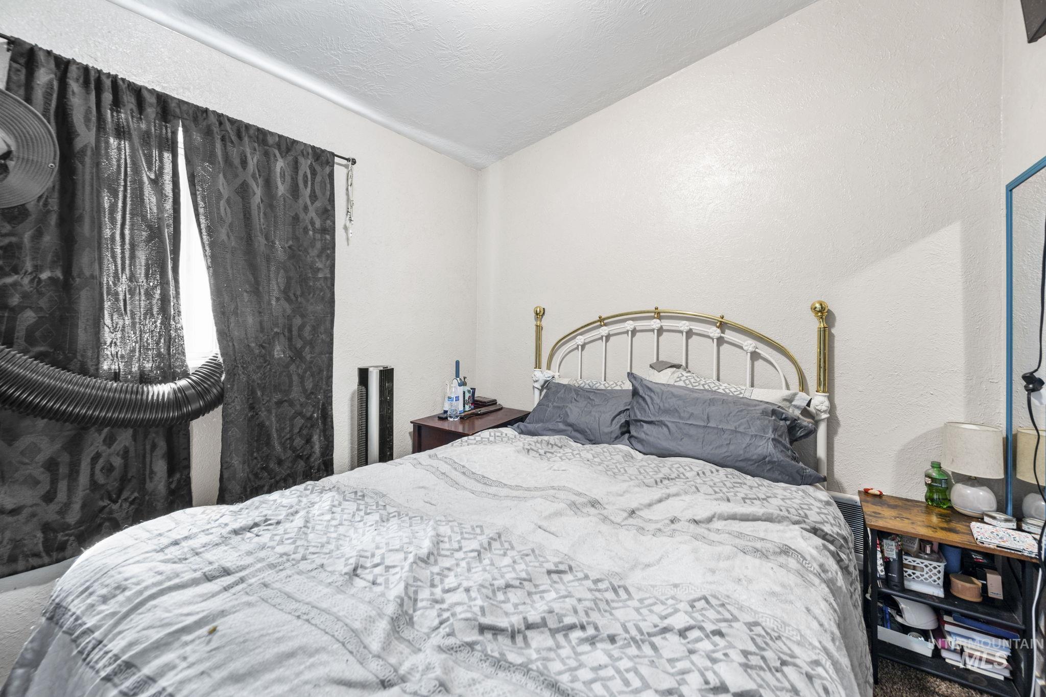 Bedroom featuring a textured wall, lofted ceiling, and a textured ceiling