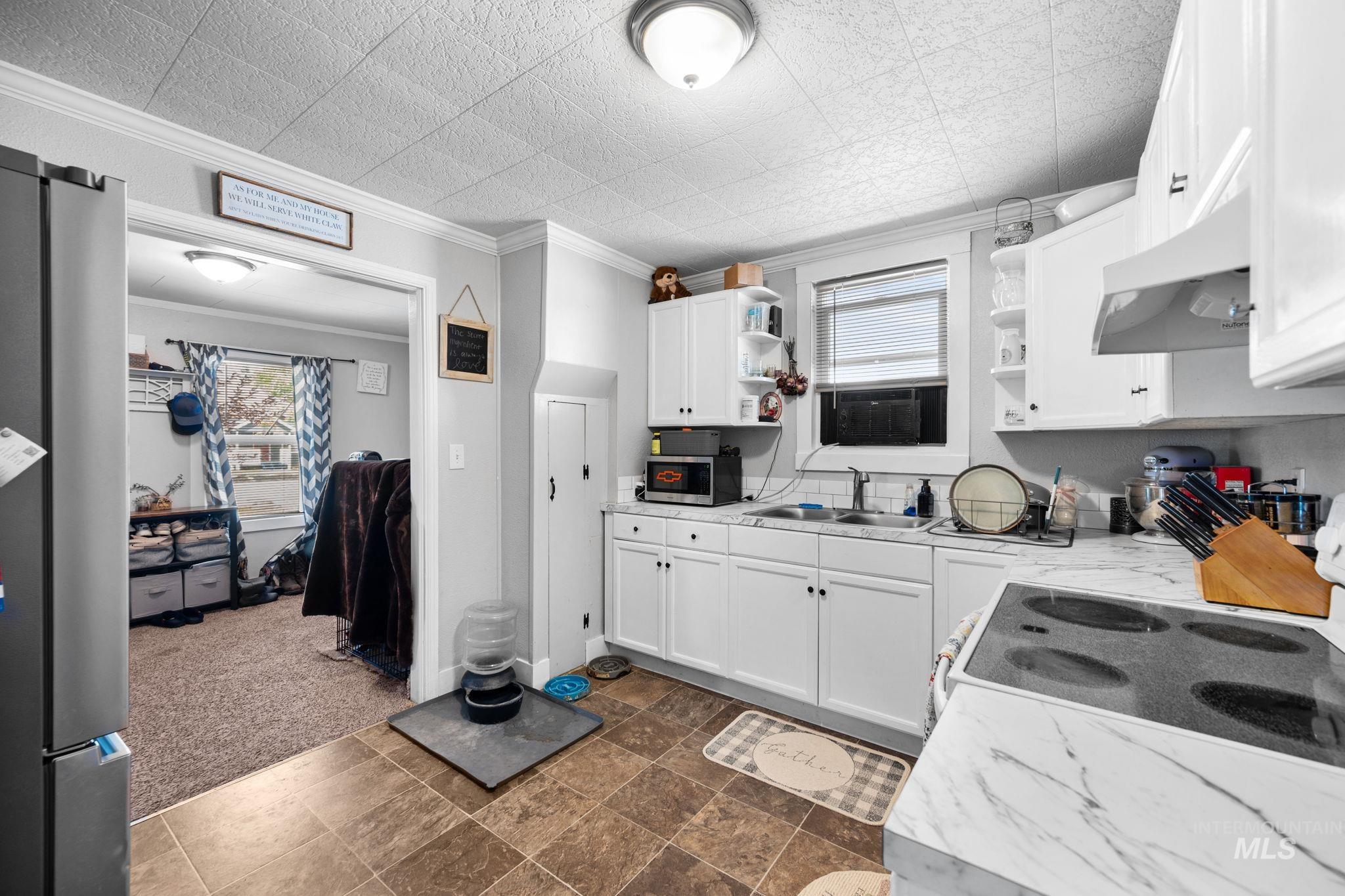 Kitchen with open shelves, light countertops, dark carpet, white cabinetry, and stainless steel appliances