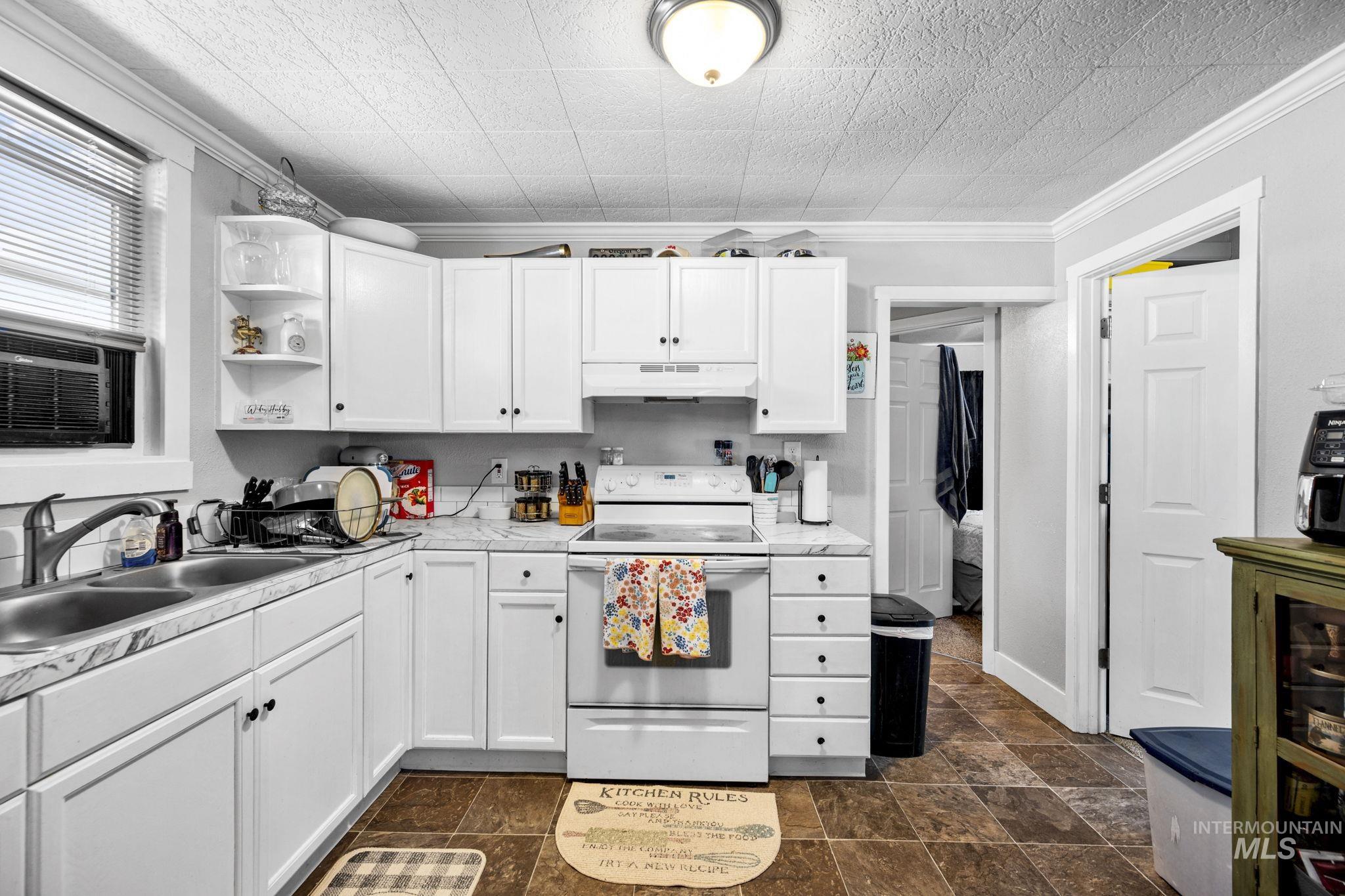 Kitchen featuring white electric range oven, white cabinets, open shelves, light countertops, and ornamental molding