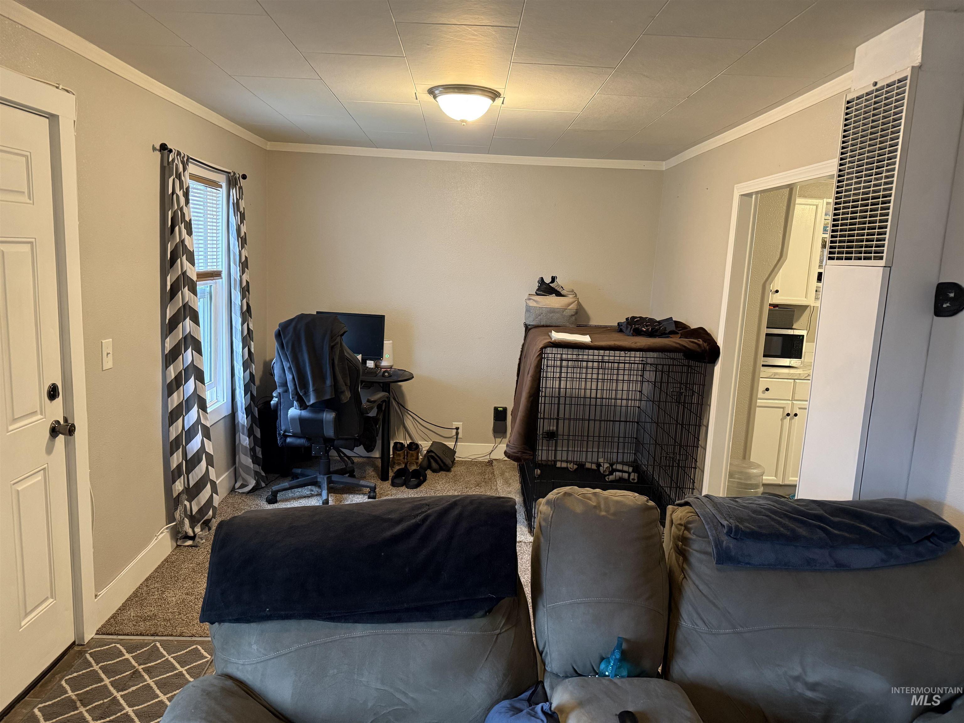 Carpeted bedroom featuring a heating unit and crown molding