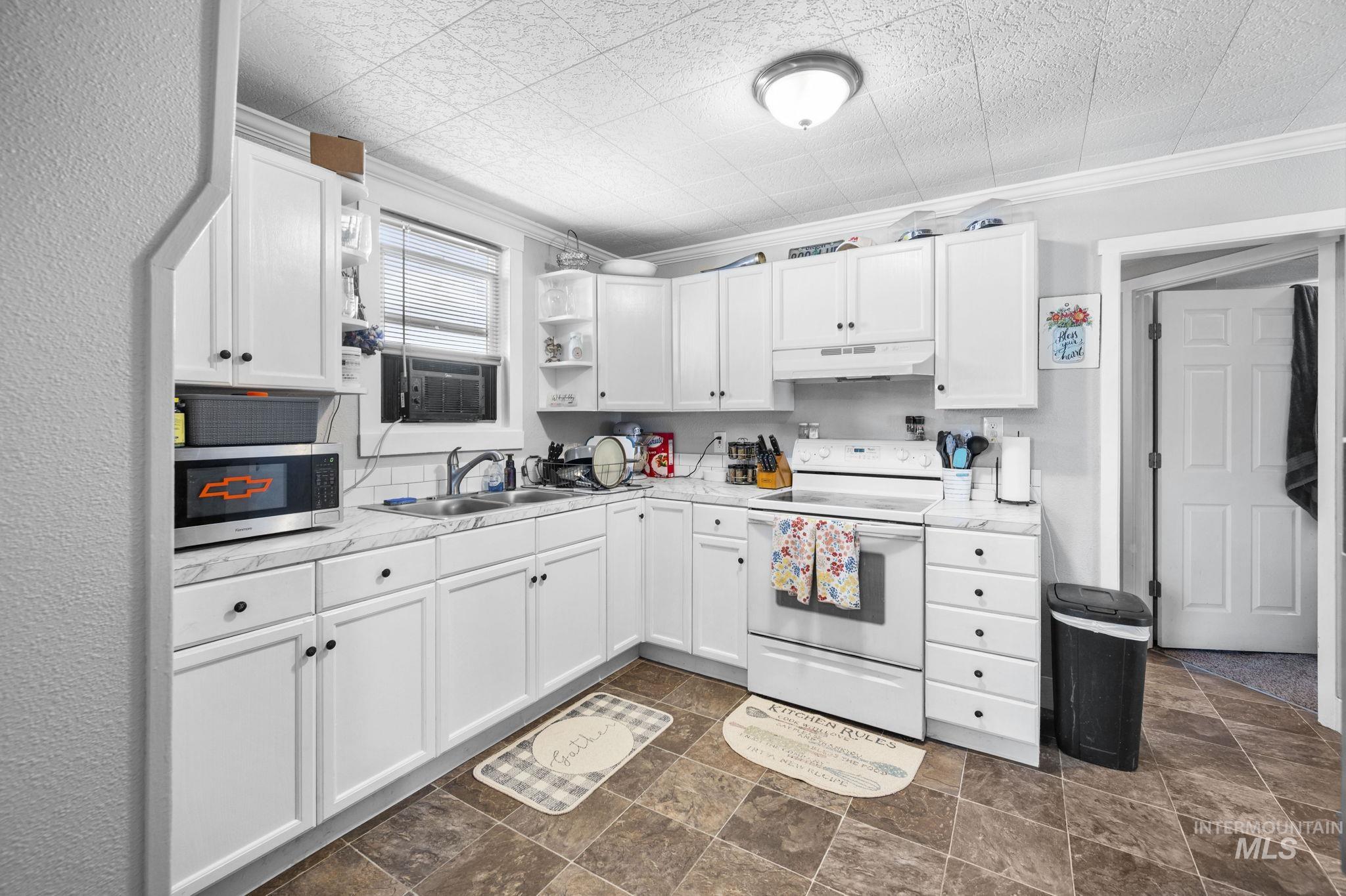 Kitchen with open shelves, white electric range, white cabinets, crown molding, and light countertops