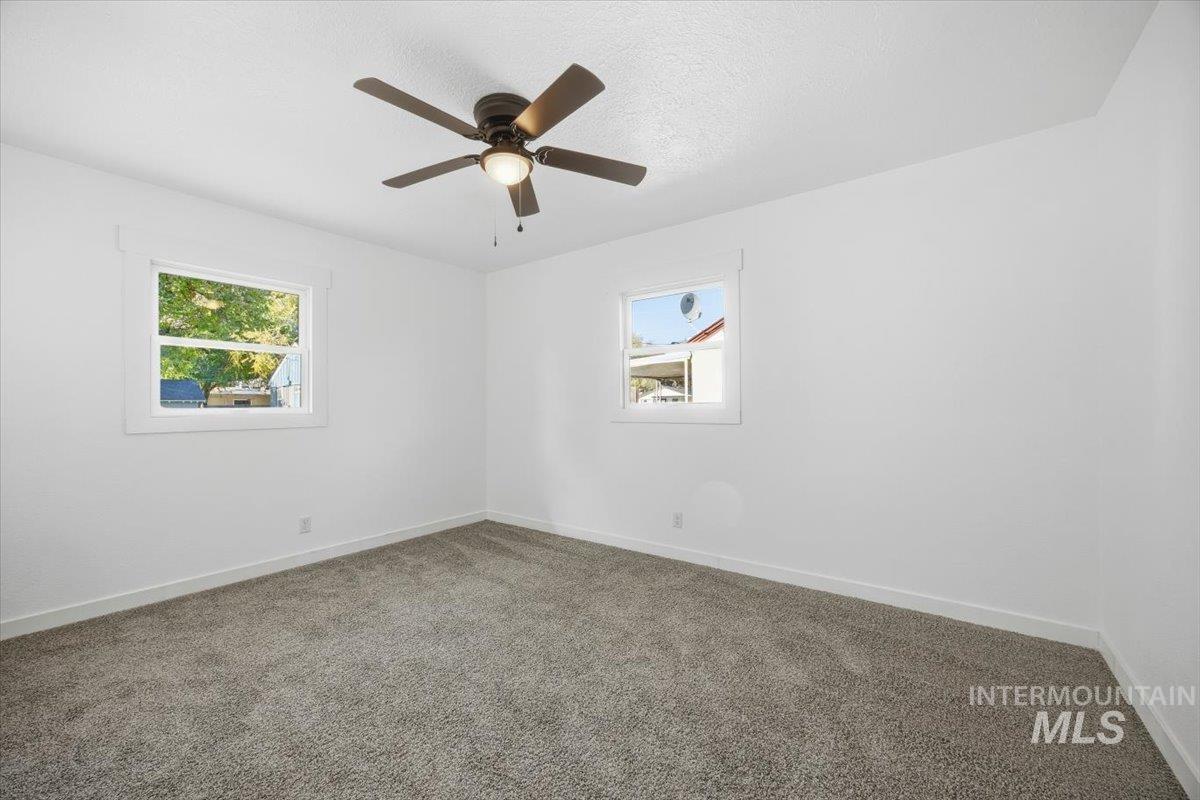 Empty room with carpet, a textured ceiling, and a ceiling fan