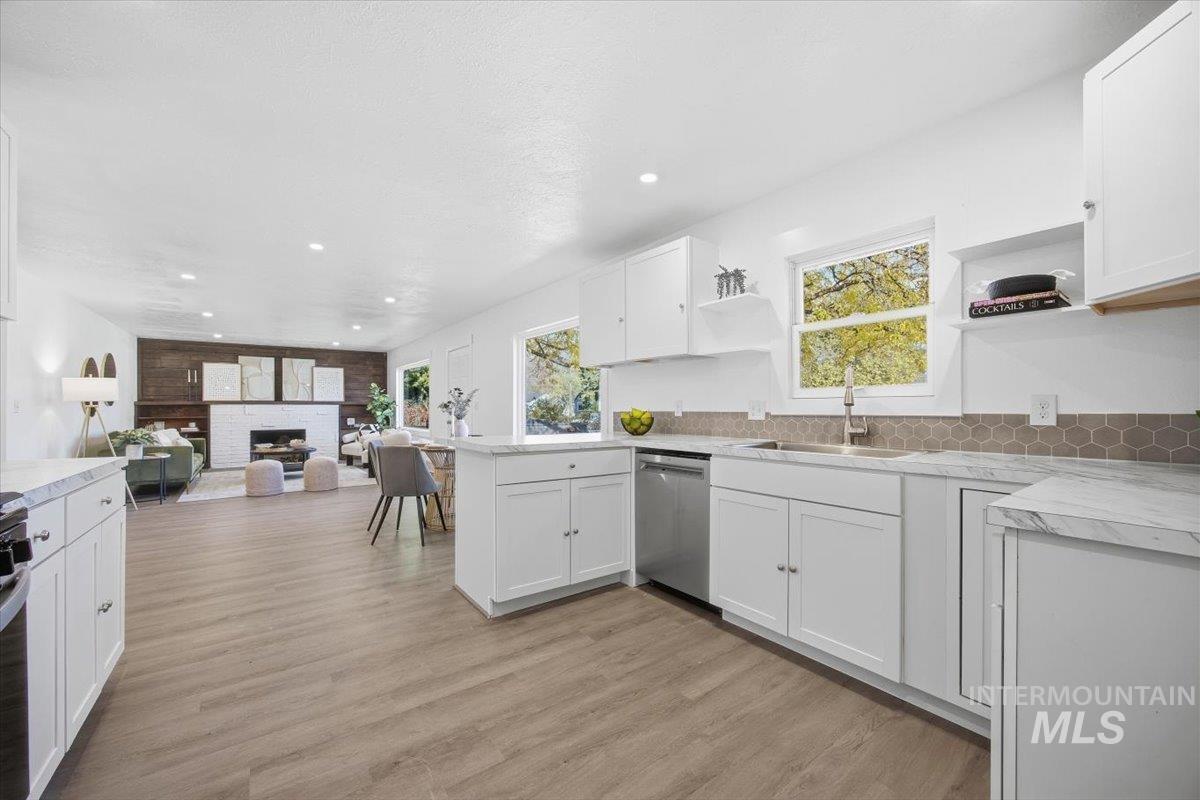 Kitchen with open shelves, white cabinetry, light countertops, a peninsula, and light wood-type flooring