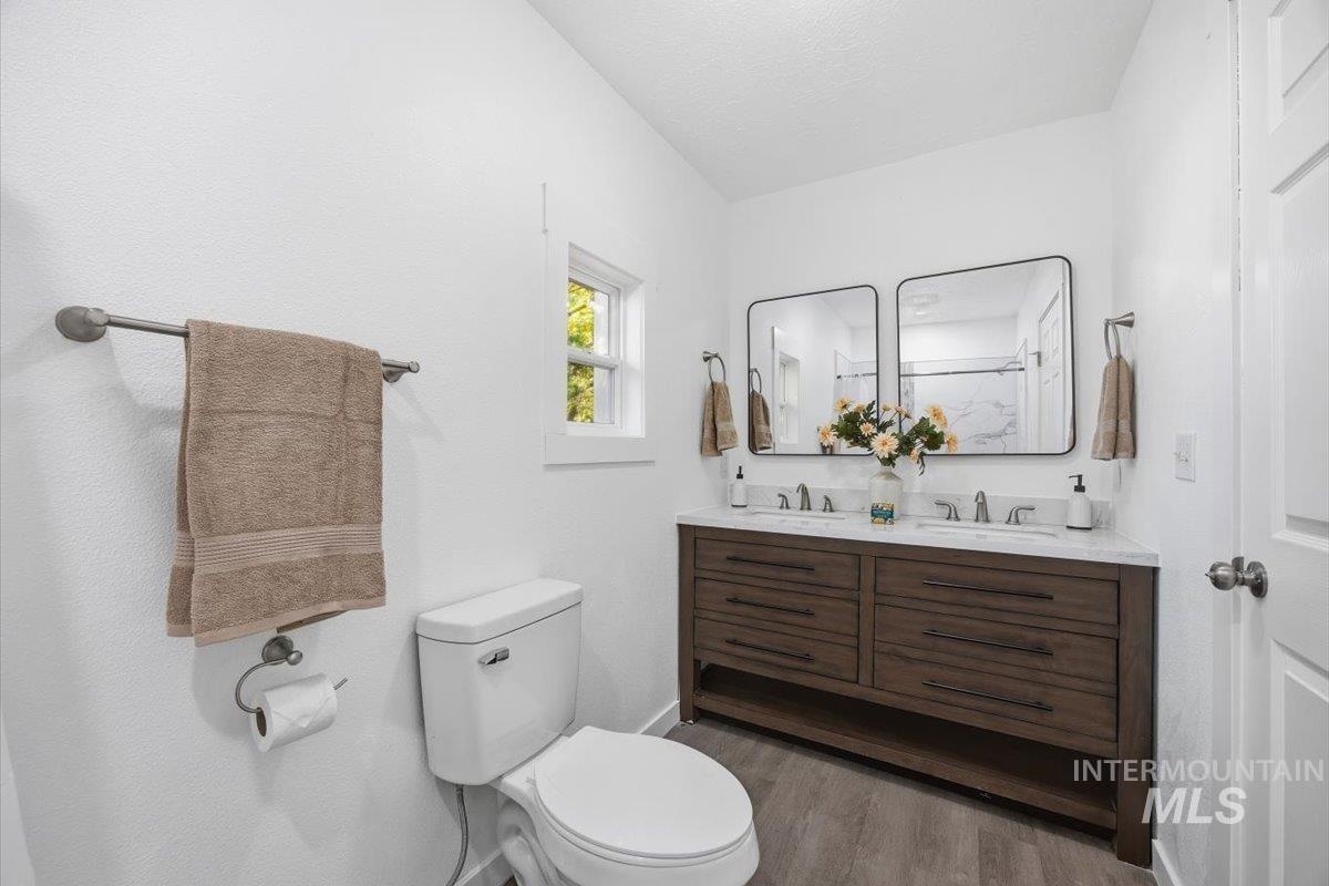 Full bathroom with double vanity and light wood-style floors