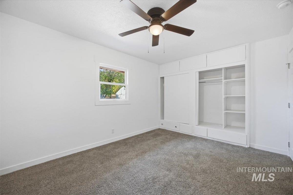 Unfurnished bedroom with carpet, a closet, ceiling fan, and a textured ceiling