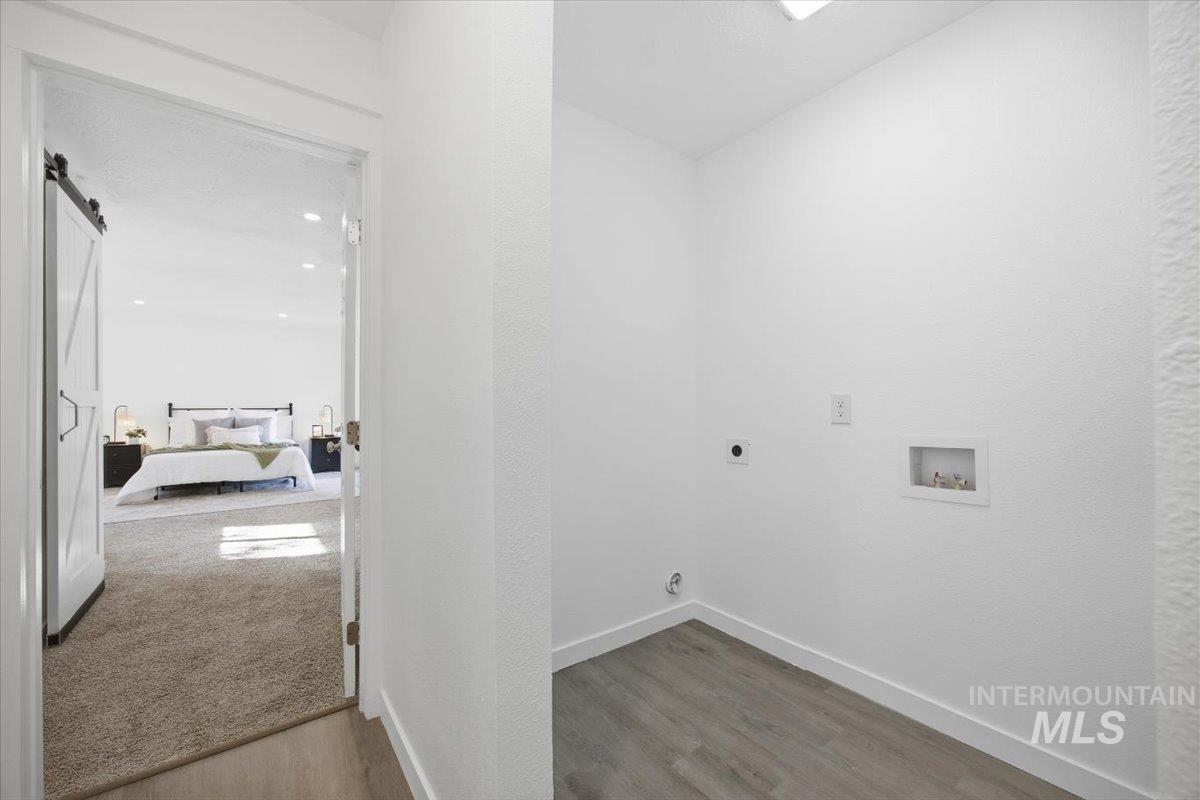 Laundry room with a barn door, wood finished floors, washer hookup, and electric dryer hookup