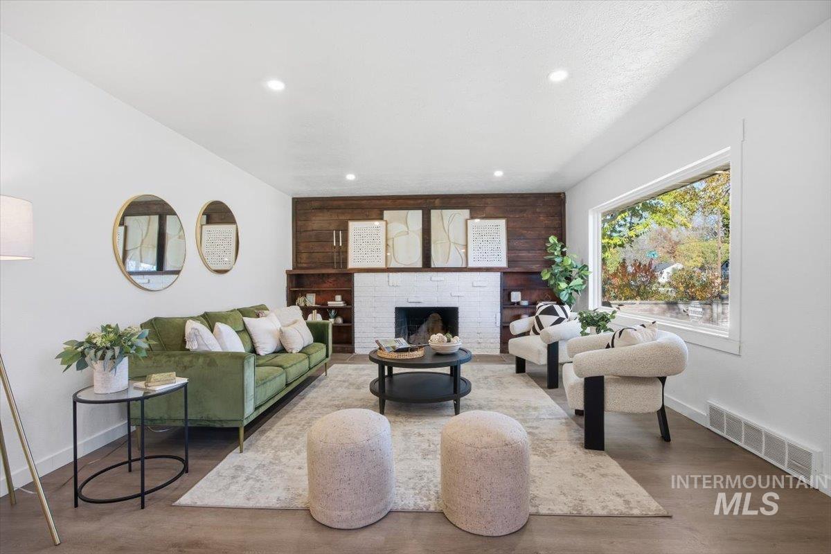 Living area with a brick fireplace, wood finished floors, and recessed lighting
