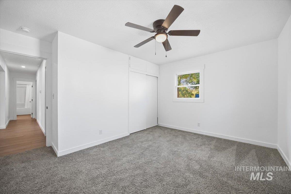 Unfurnished bedroom with carpet, a closet, ceiling fan, and a textured ceiling