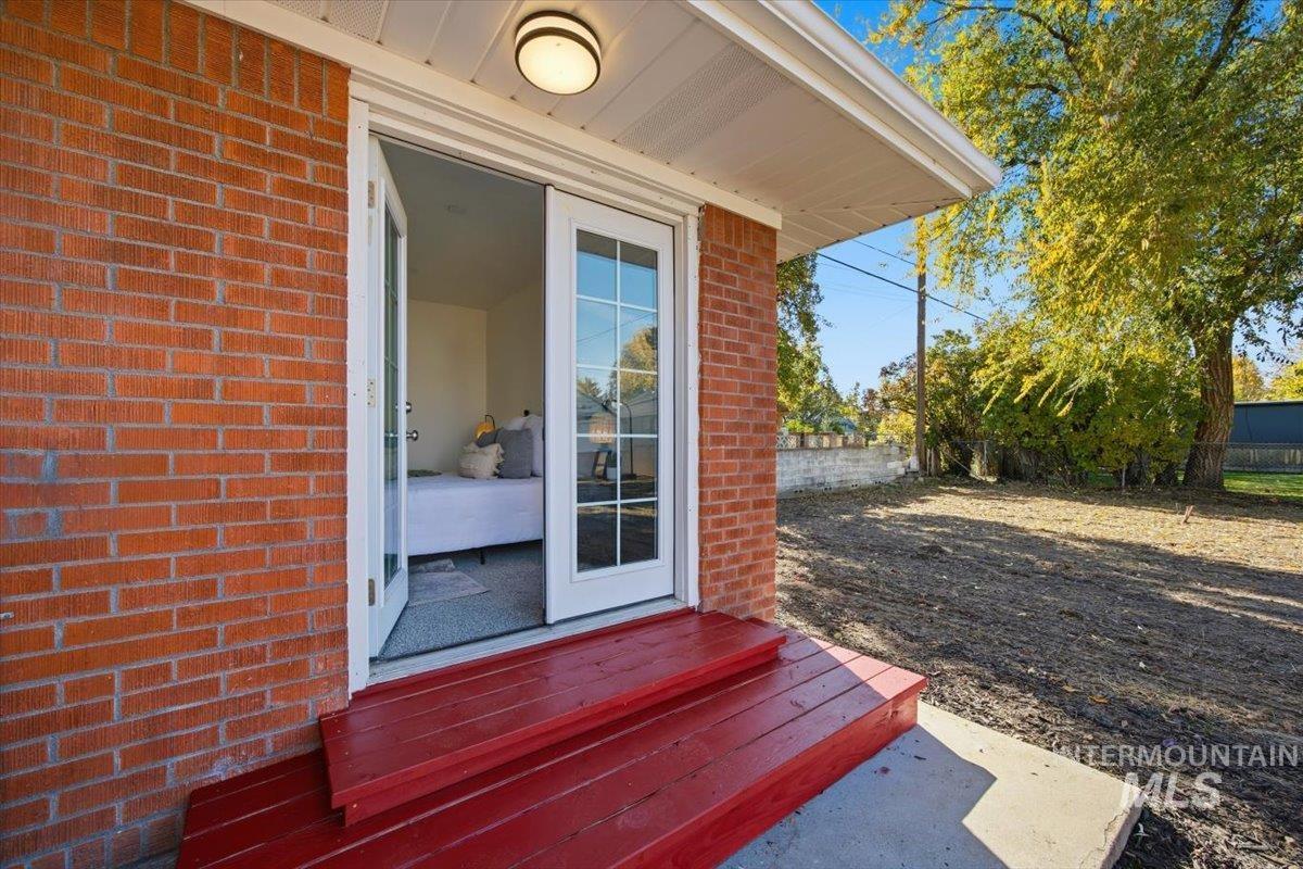 View of exterior entry featuring brick siding and a deck