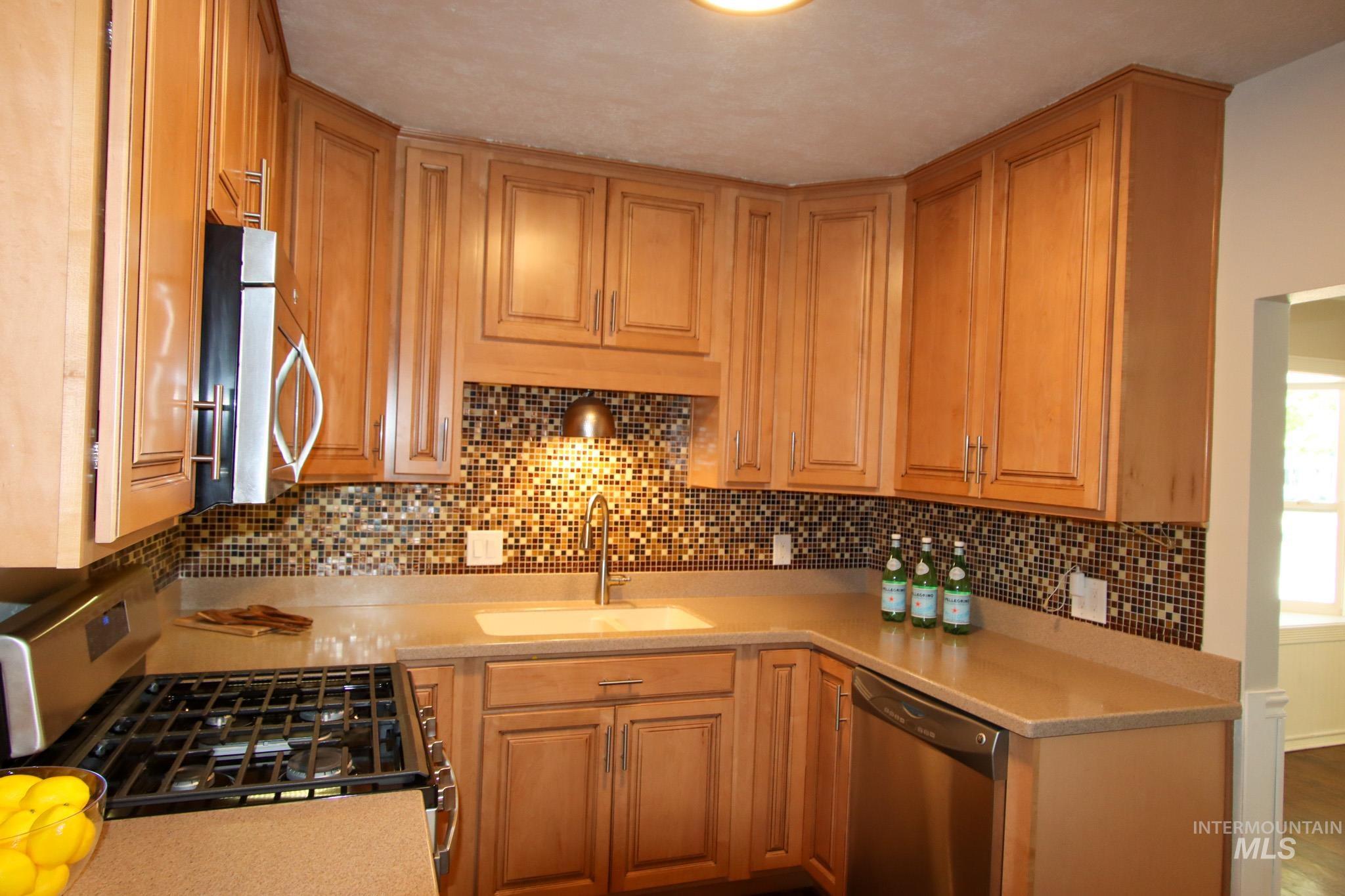 Kitchen featuring appliances with stainless steel finishes, backsplash, and light stone countertops