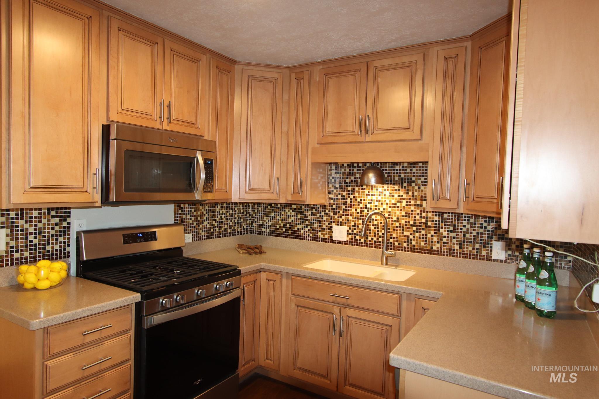 Kitchen featuring stainless steel appliances, tasteful backsplash, and light stone counters