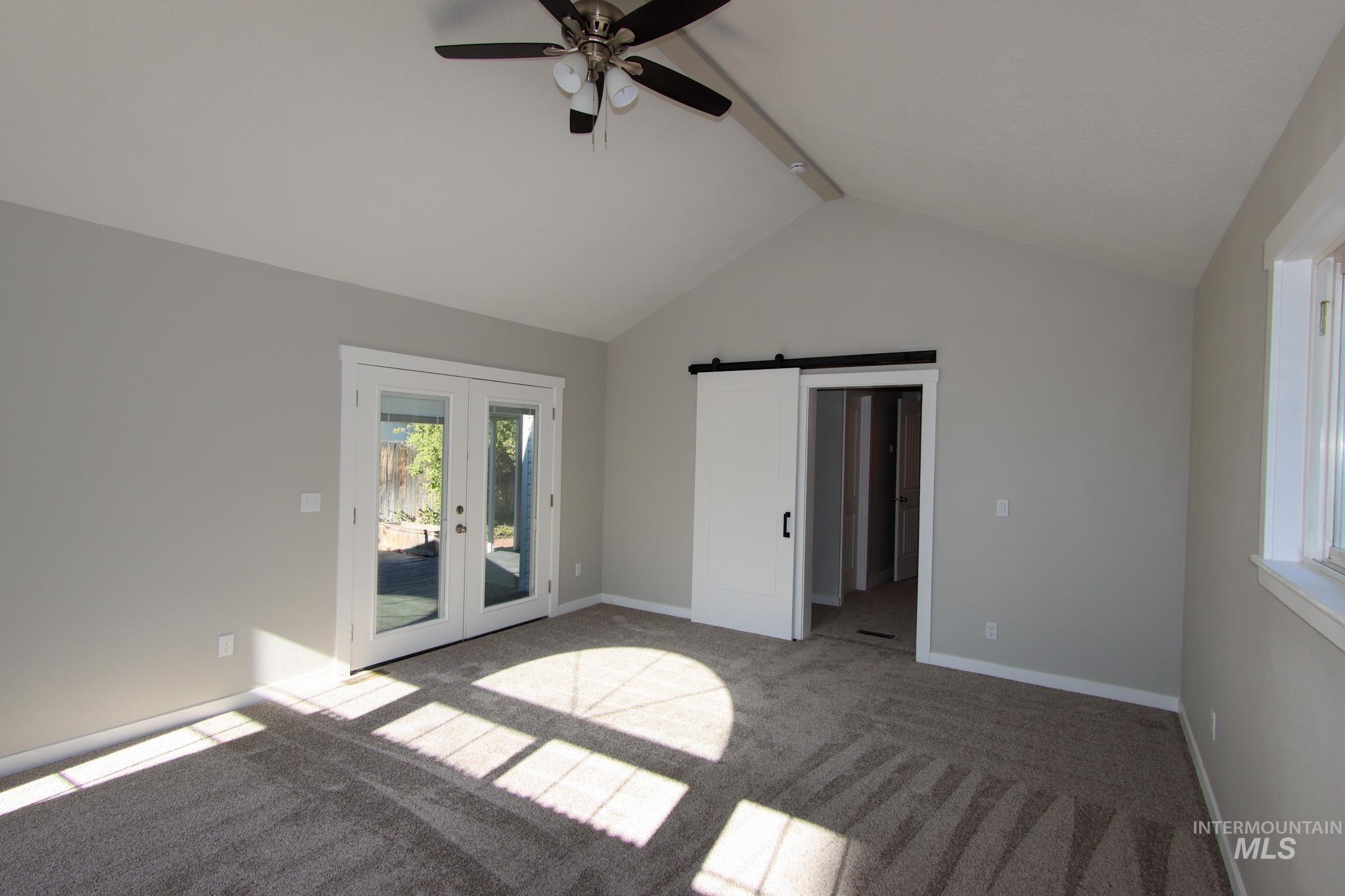 Unfurnished bedroom with a barn door, beam ceiling, french doors, carpet flooring, and access to outside