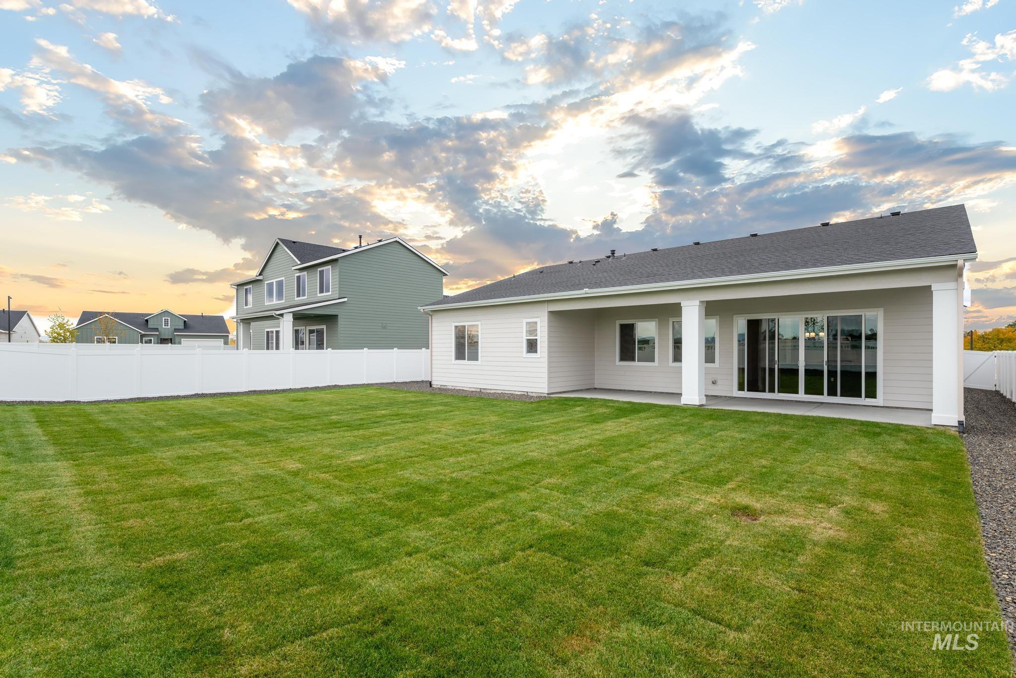 Back of house at dusk with a fenced backyard and a patio