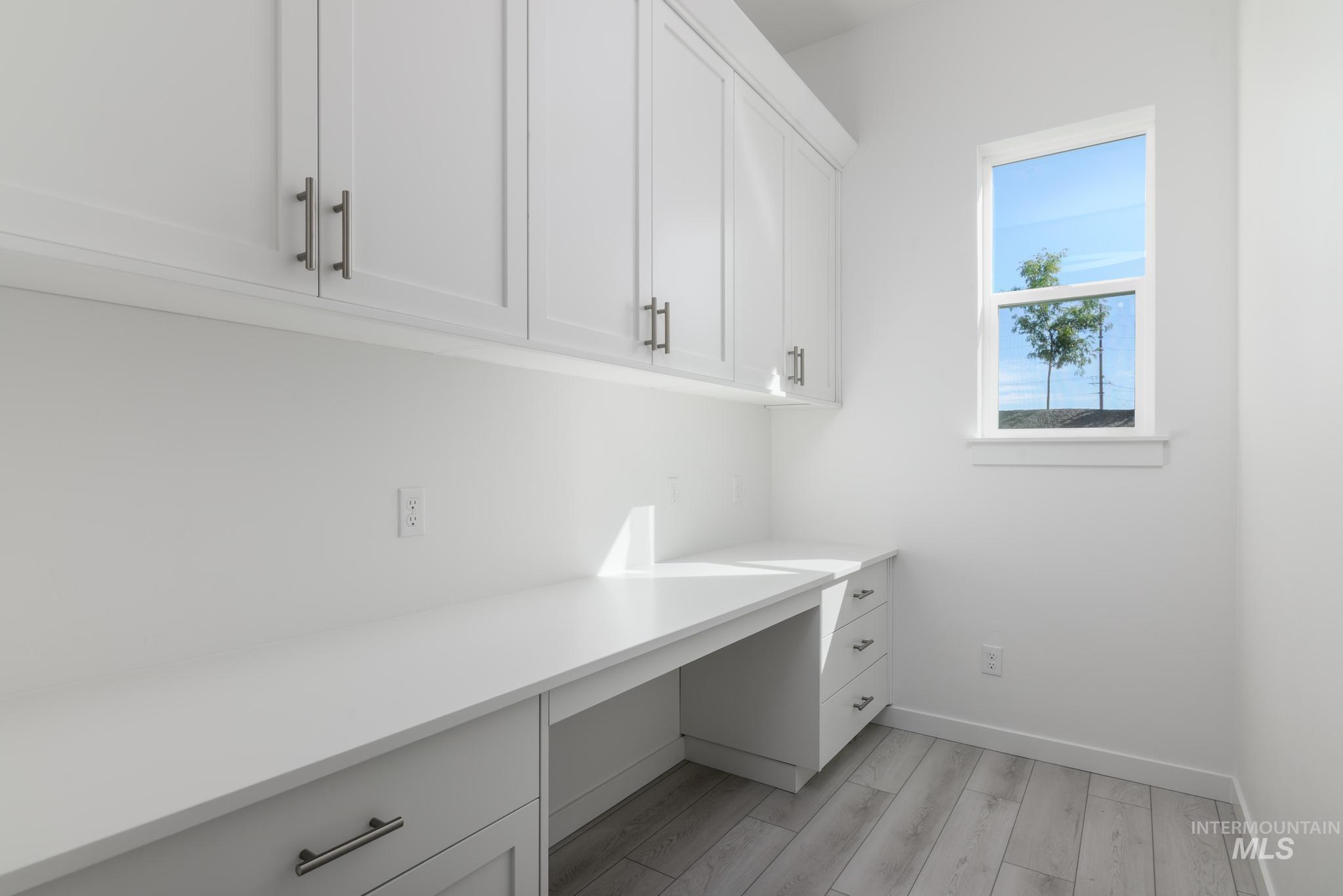 Unfurnished office with built in desk and light wood-style floors