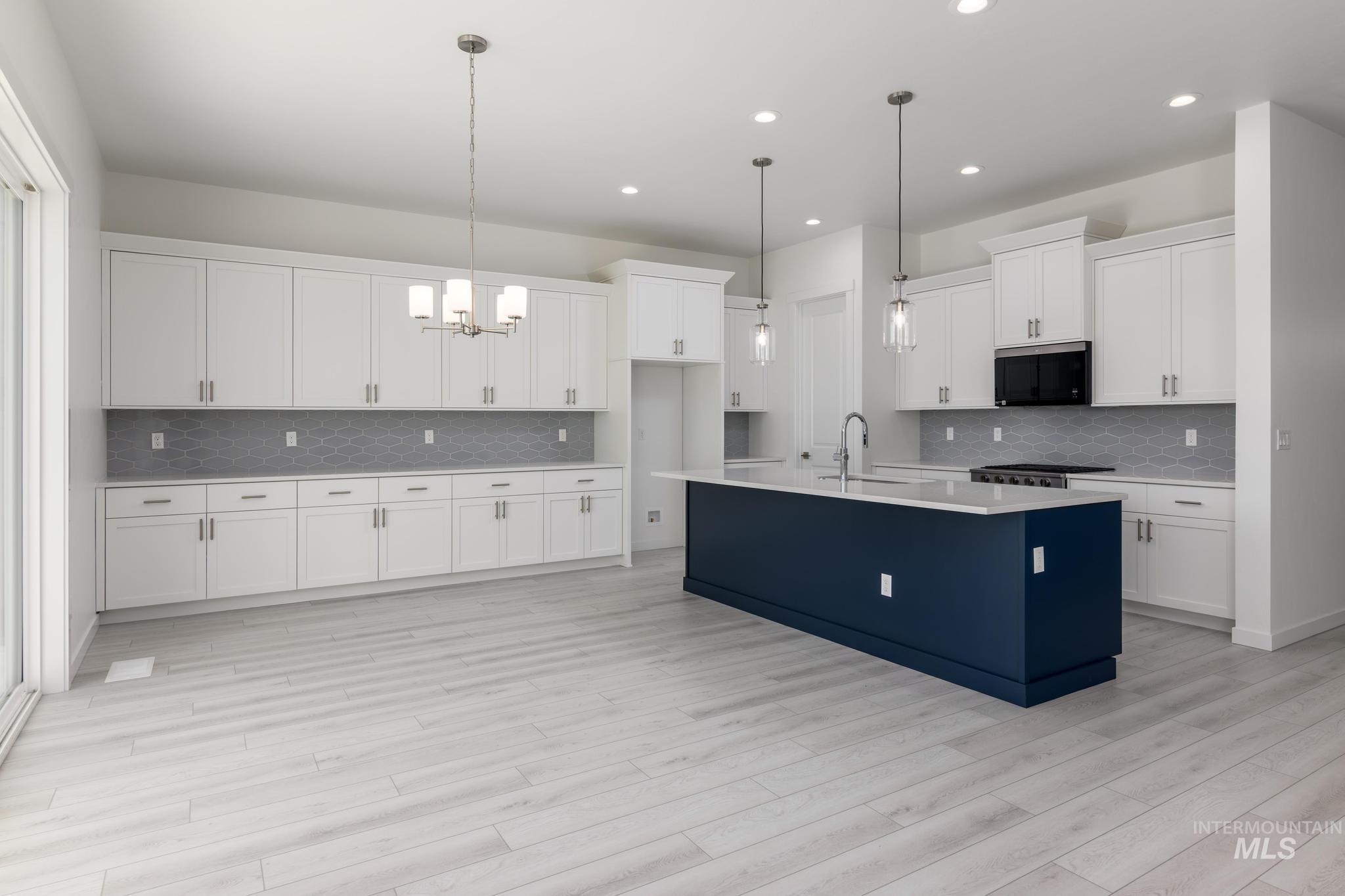 Kitchen with pendant lighting, backsplash, white cabinets, a chandelier, and recessed lighting