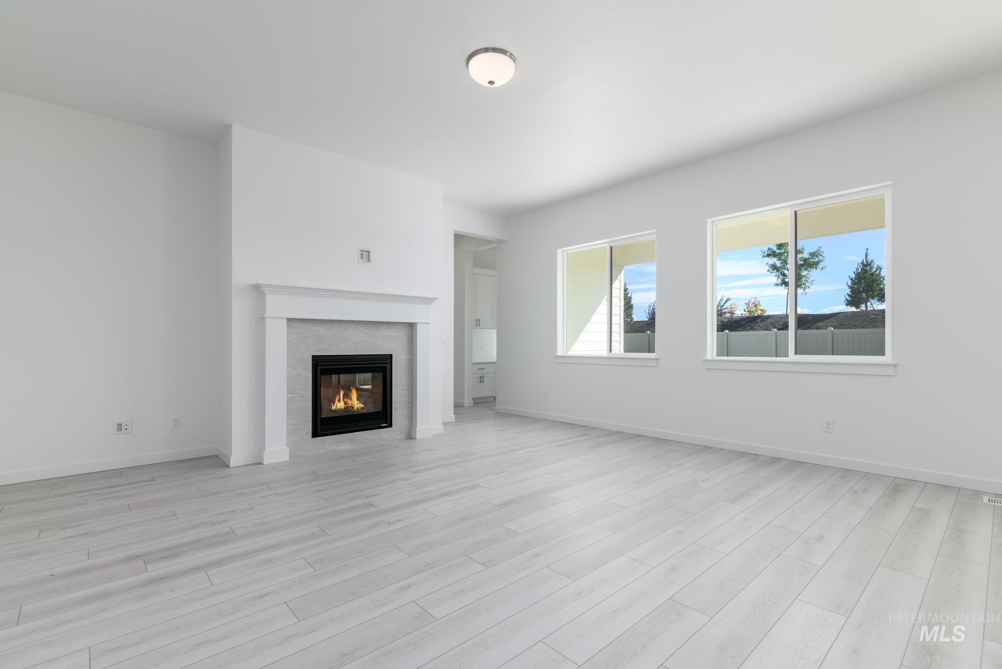 Unfurnished living room featuring a tile fireplace and light wood finished floors
