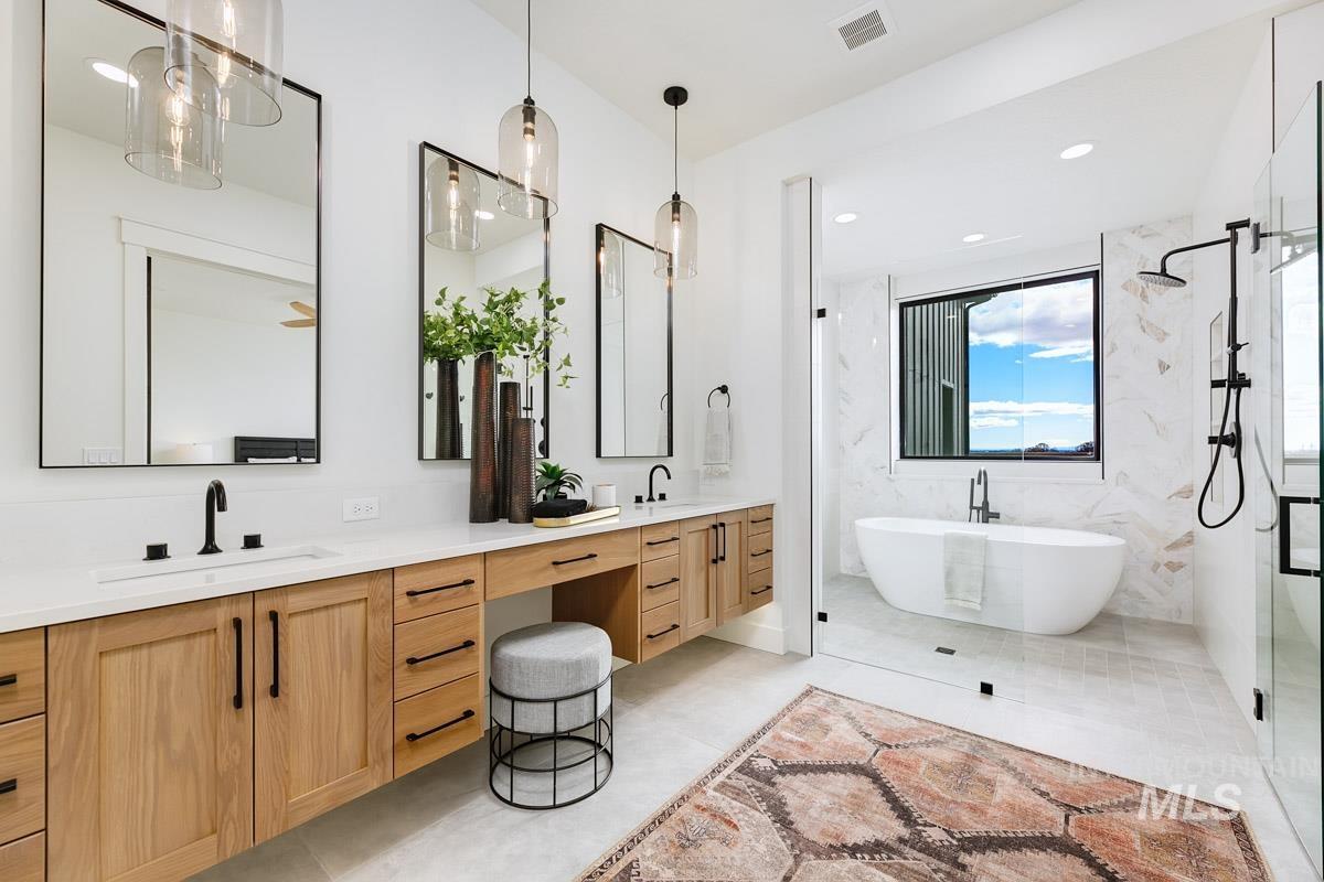 Bathroom featuring a marble finish shower, double vanity, a freestanding tub, and recessed lighting