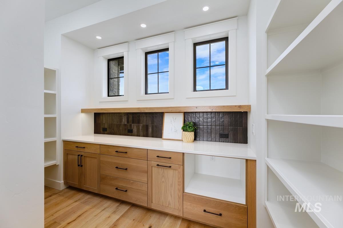 Bar featuring light wood-style floors, recessed lighting, and brown cabinetry