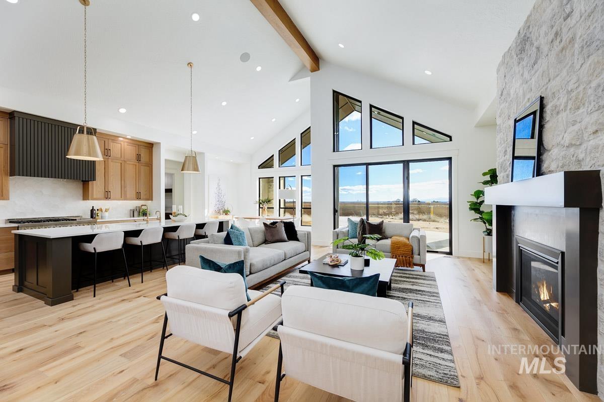 Living room featuring high vaulted ceiling, light wood-style flooring, a large fireplace, beamed ceiling, and recessed lighting