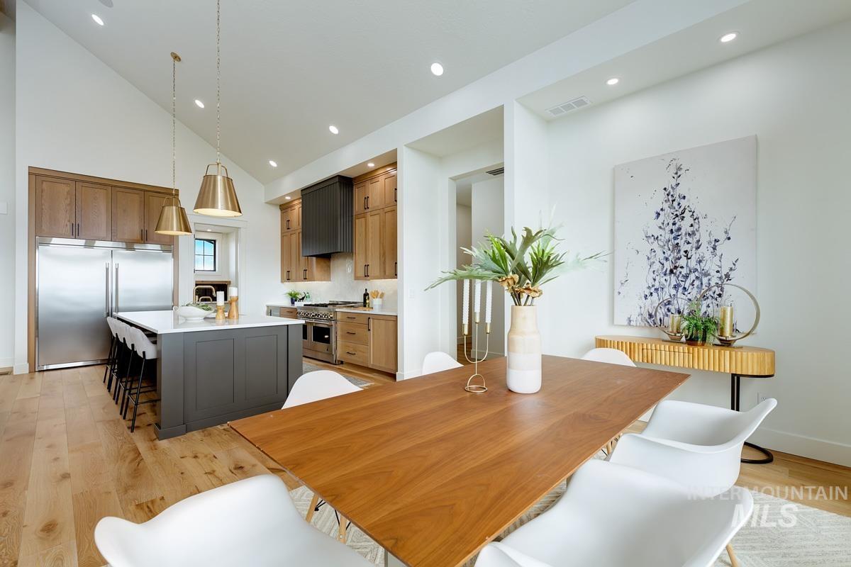 Dining room featuring light wood-type flooring, high vaulted ceiling, and recessed lighting