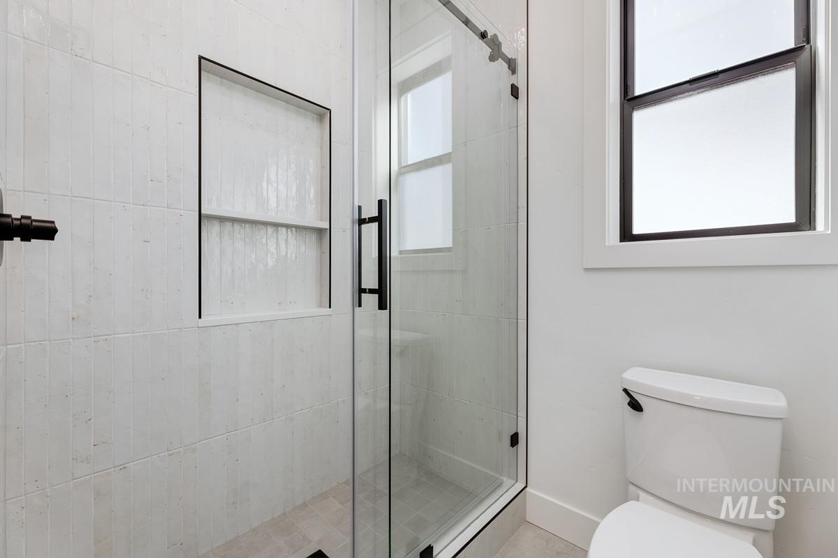 Full bathroom featuring a shower stall and toilet