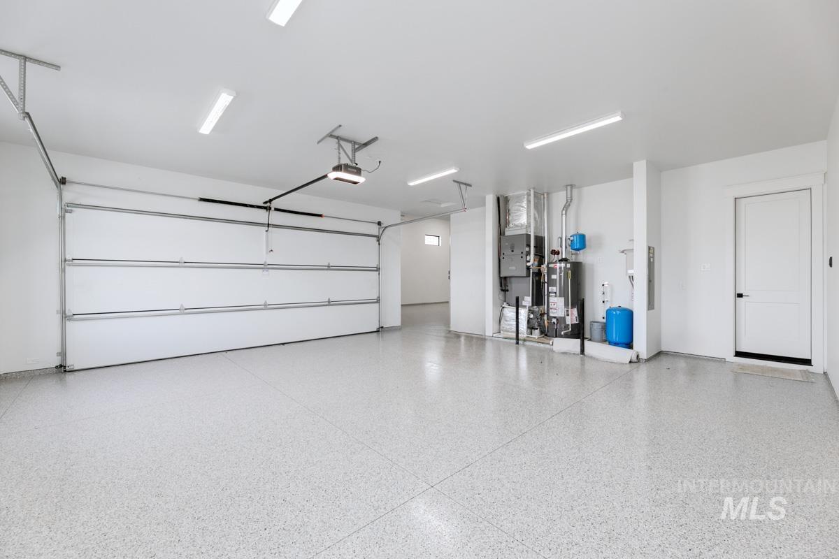Garage featuring gas water heater, electric panel, heating unit, and a garage door opener