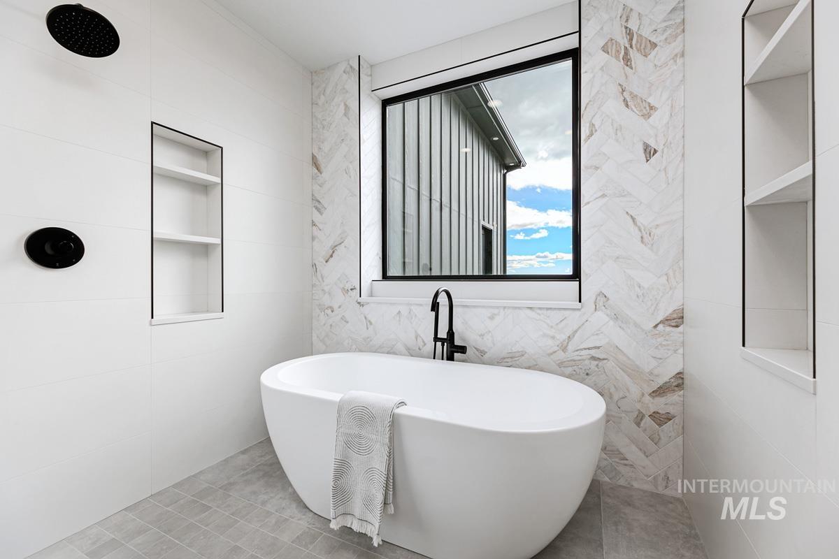 Full bath featuring tile walls, a freestanding bath, and built in shelves