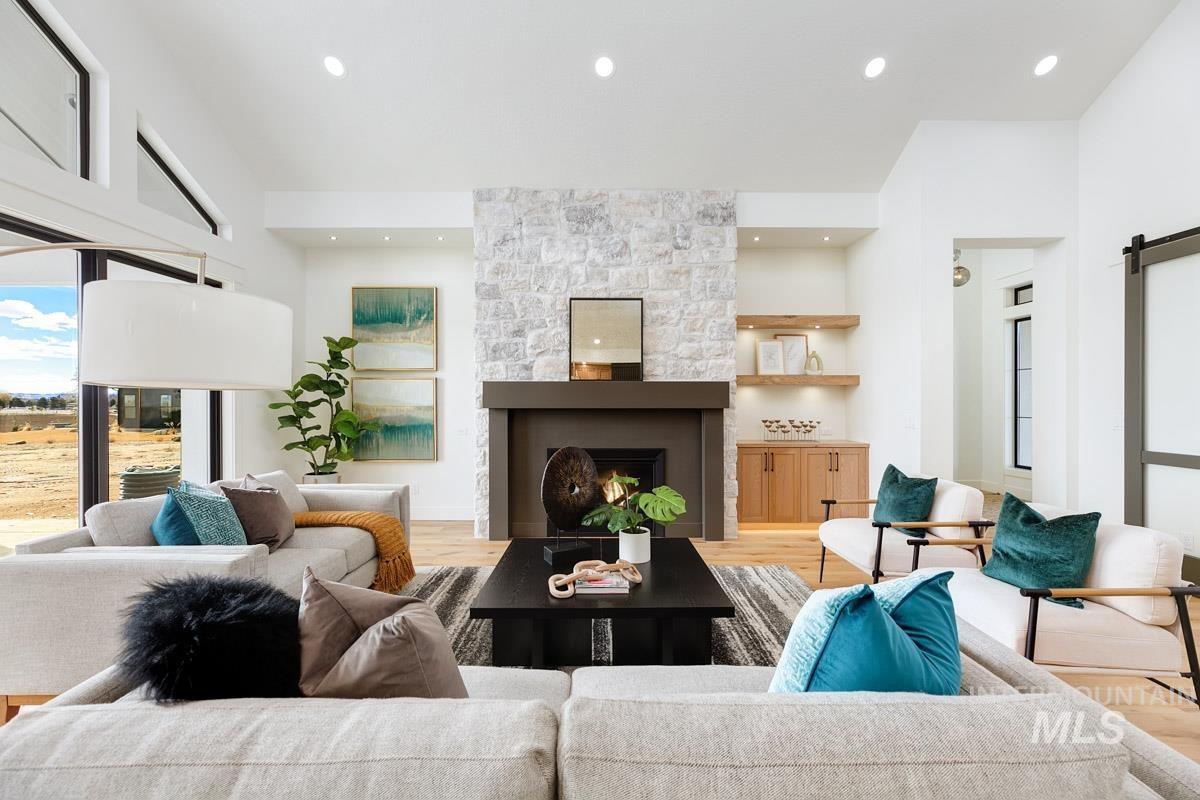 Living area with a barn door, light wood-type flooring, a stone fireplace, and recessed lighting