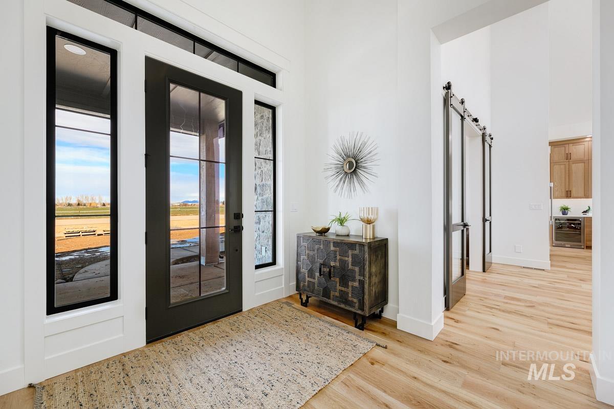 Foyer entrance with a barn door, beverage cooler, light wood-style flooring, and a high ceiling