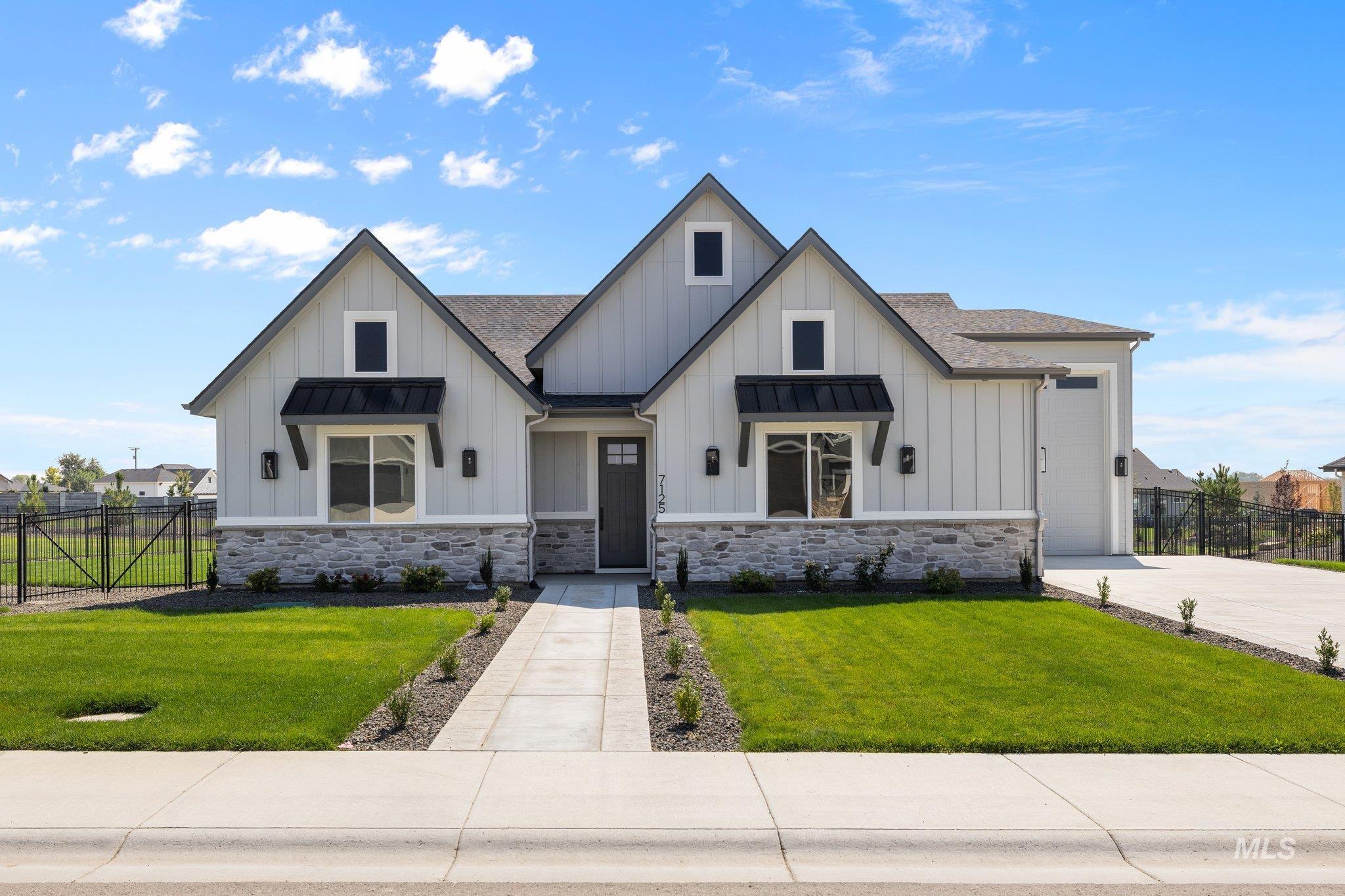 Modern farmhouse with board and batten siding, a shingled roof, a standing seam roof, driveway, and stone siding