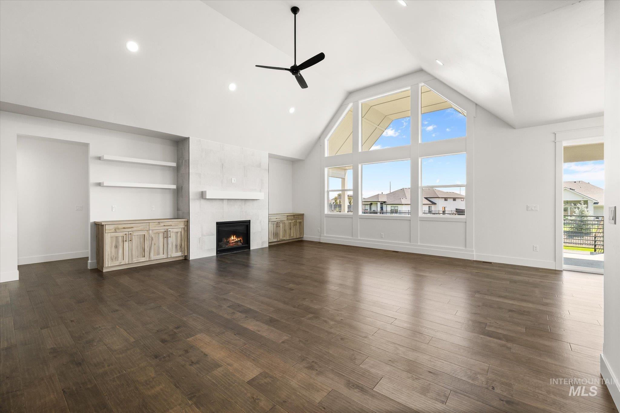 Unfurnished living room with high vaulted ceiling, dark wood finished floors, a fireplace, a ceiling fan, and recessed lighting