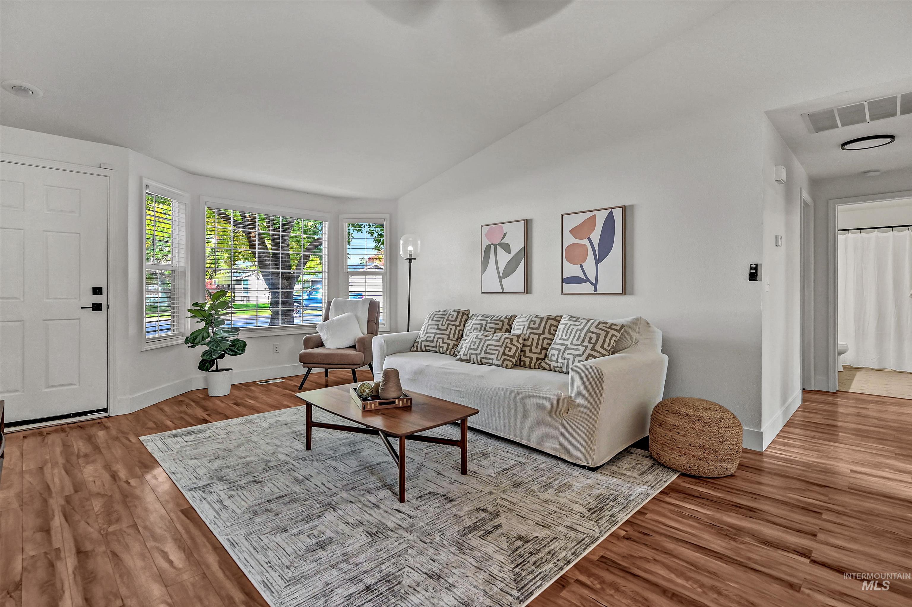 Living area with vaulted ceiling and light wood-style floors