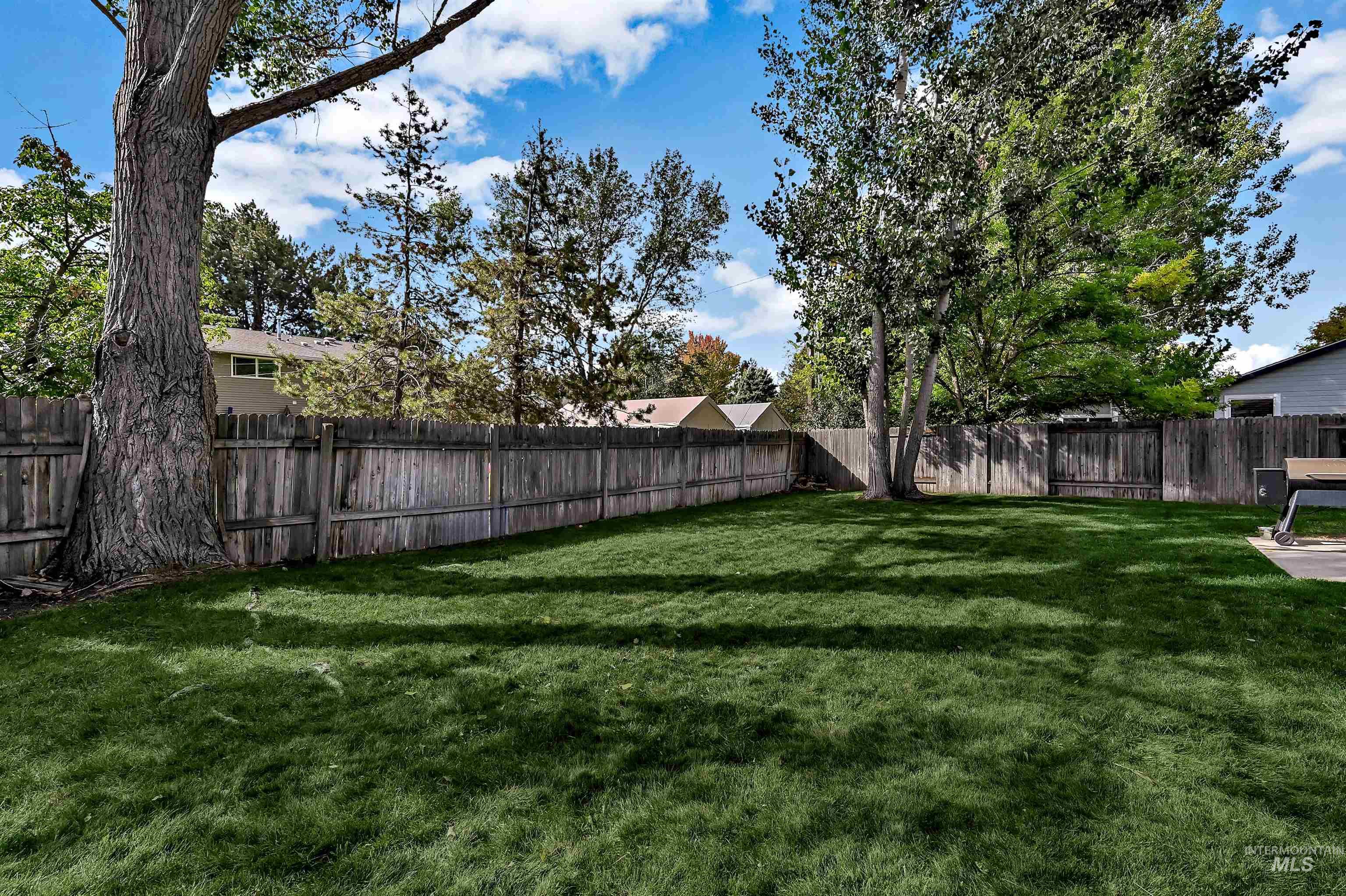View of large fenced backyard with mature trees