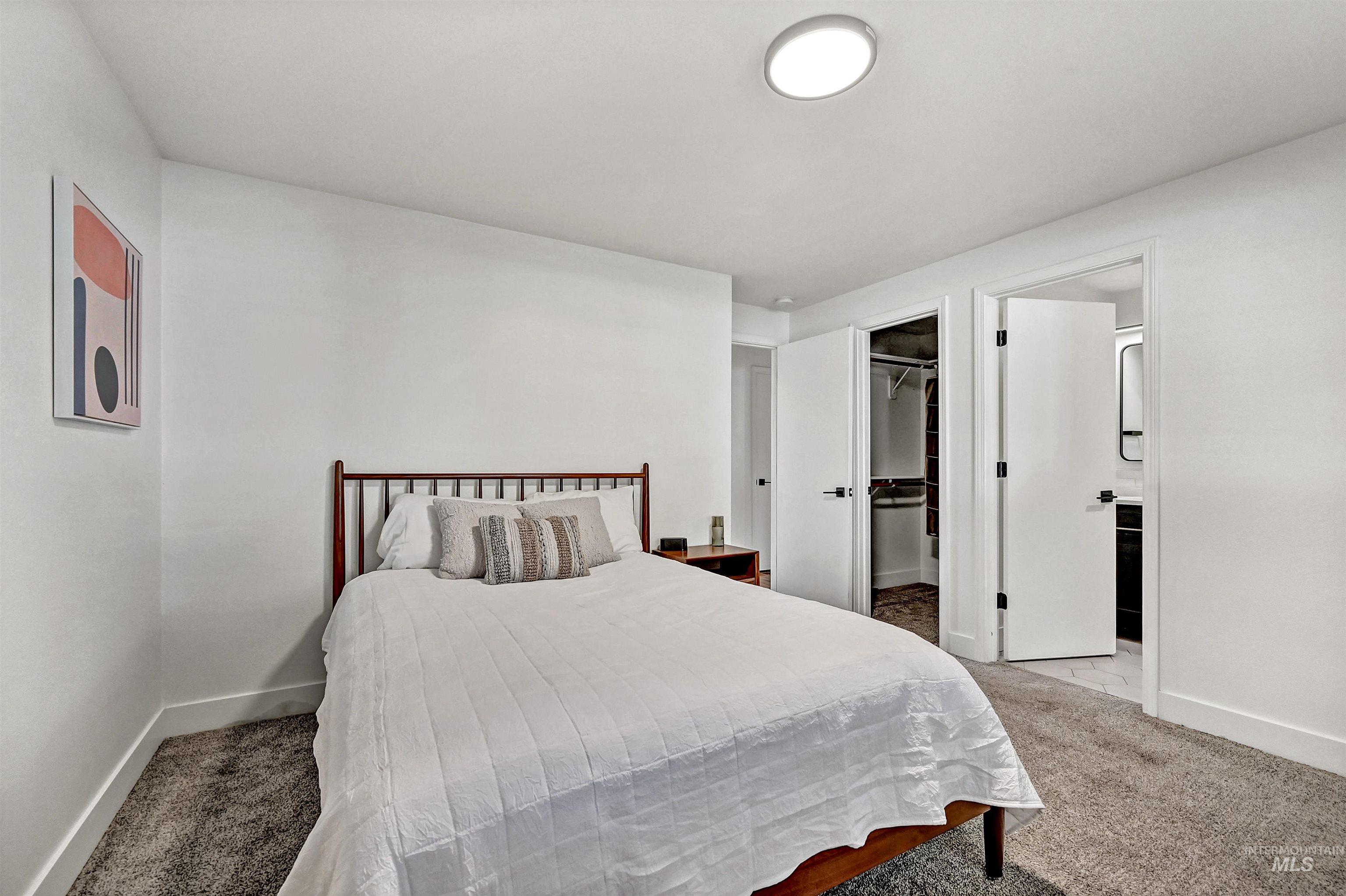 Primary ensuite with large windows, carpeting, a walk-in closet & fresh paint