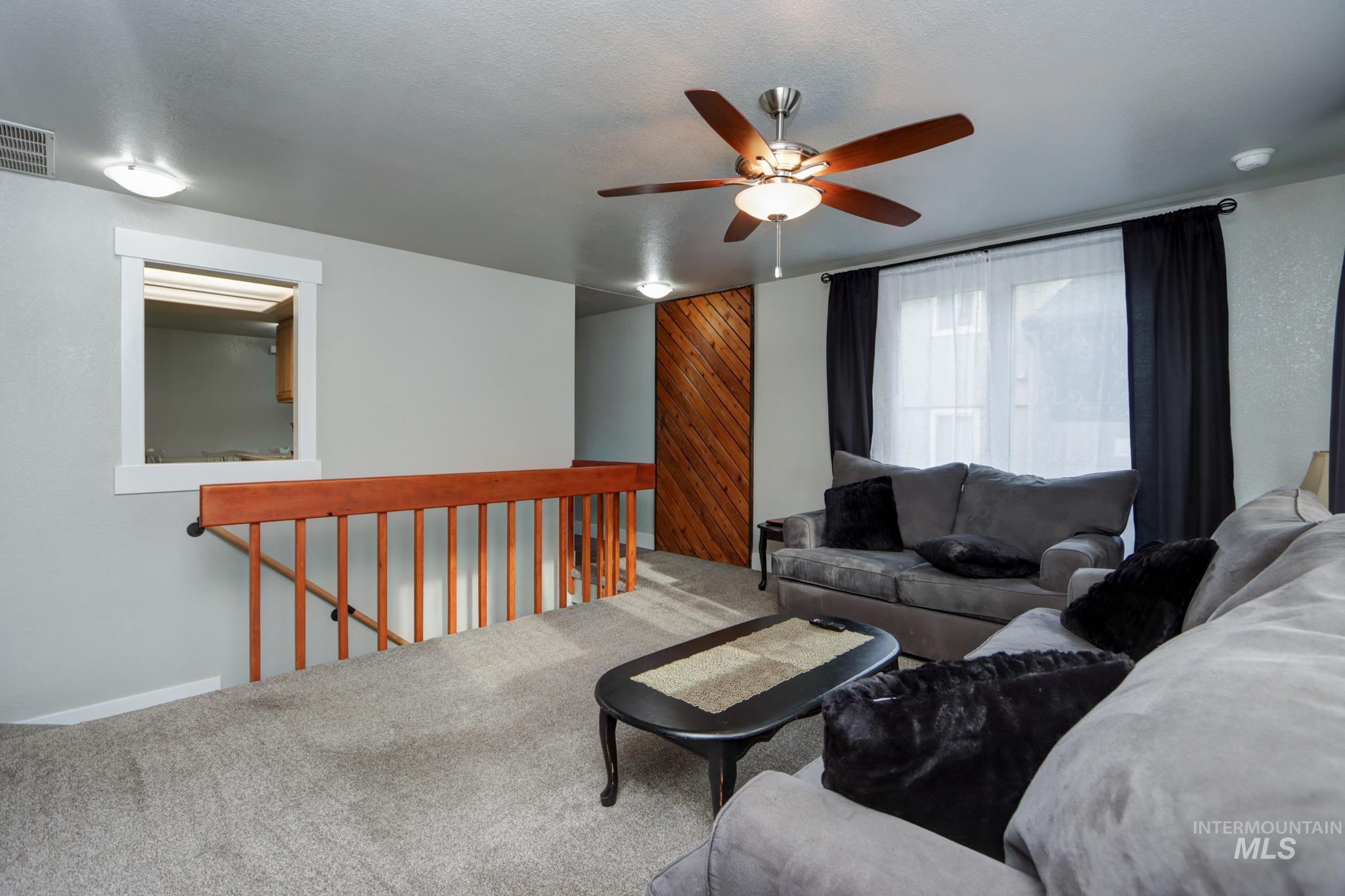 Living area featuring carpet floors, a ceiling fan, and wooden walls
