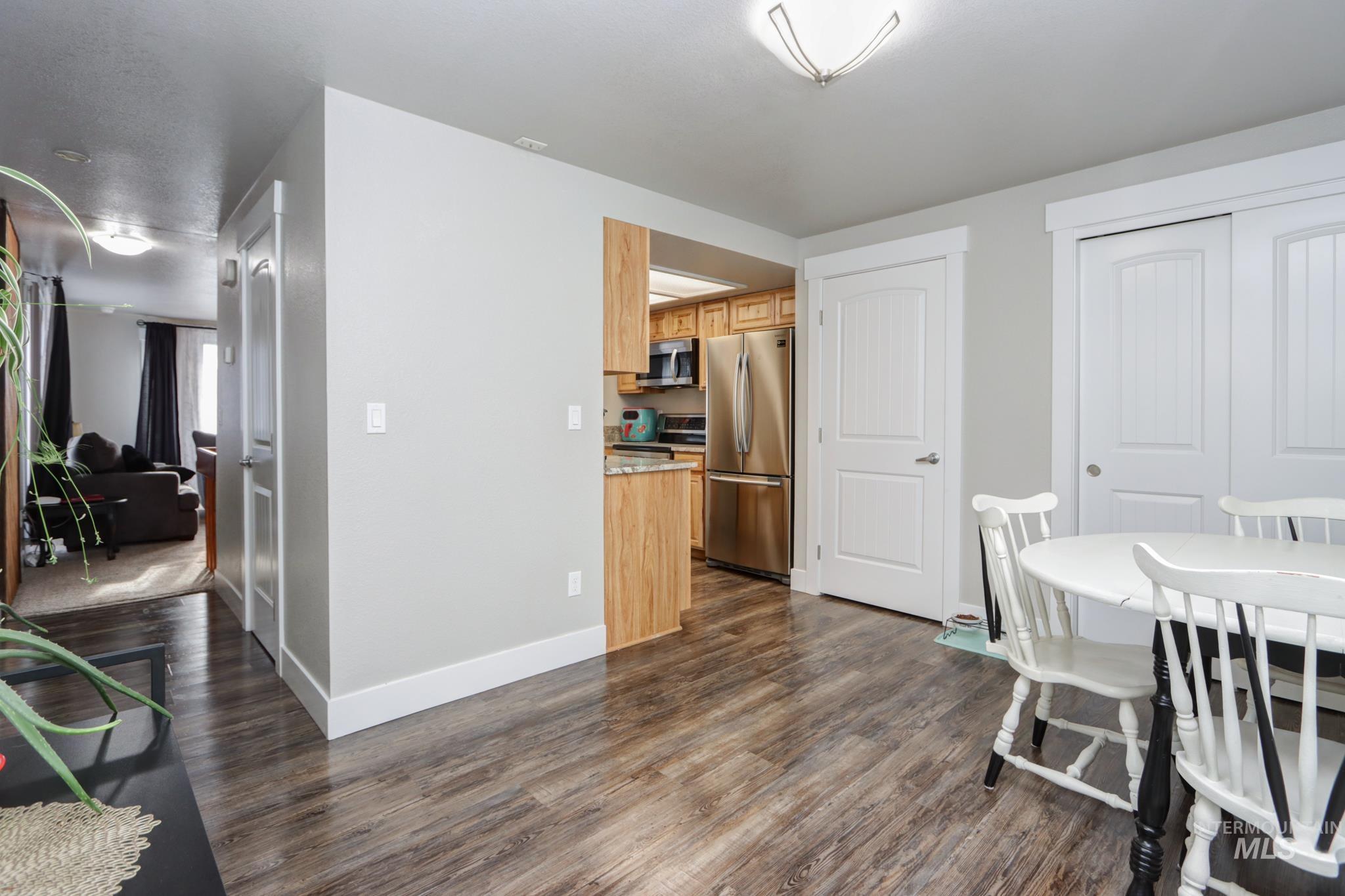Dining space with dark wood-style flooring and baseboards