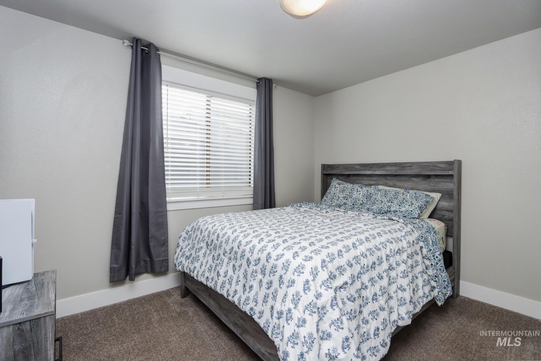 Bedroom with dark colored carpet and baseboards