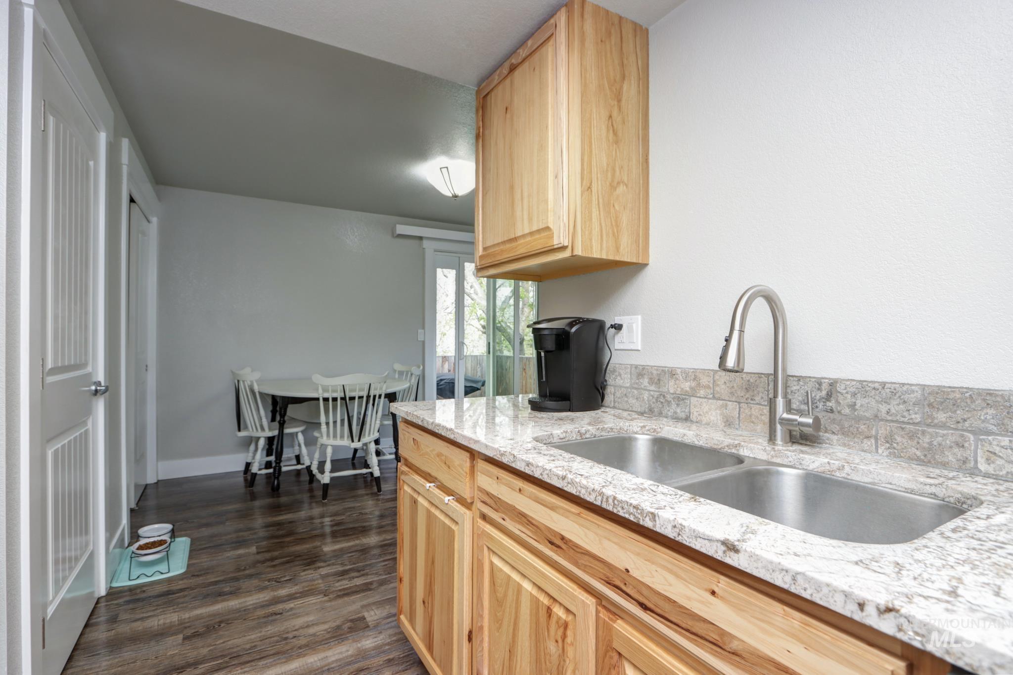 Kitchen featuring light wood finish cabinetry, light stone countertops, and dark wood-style flooring