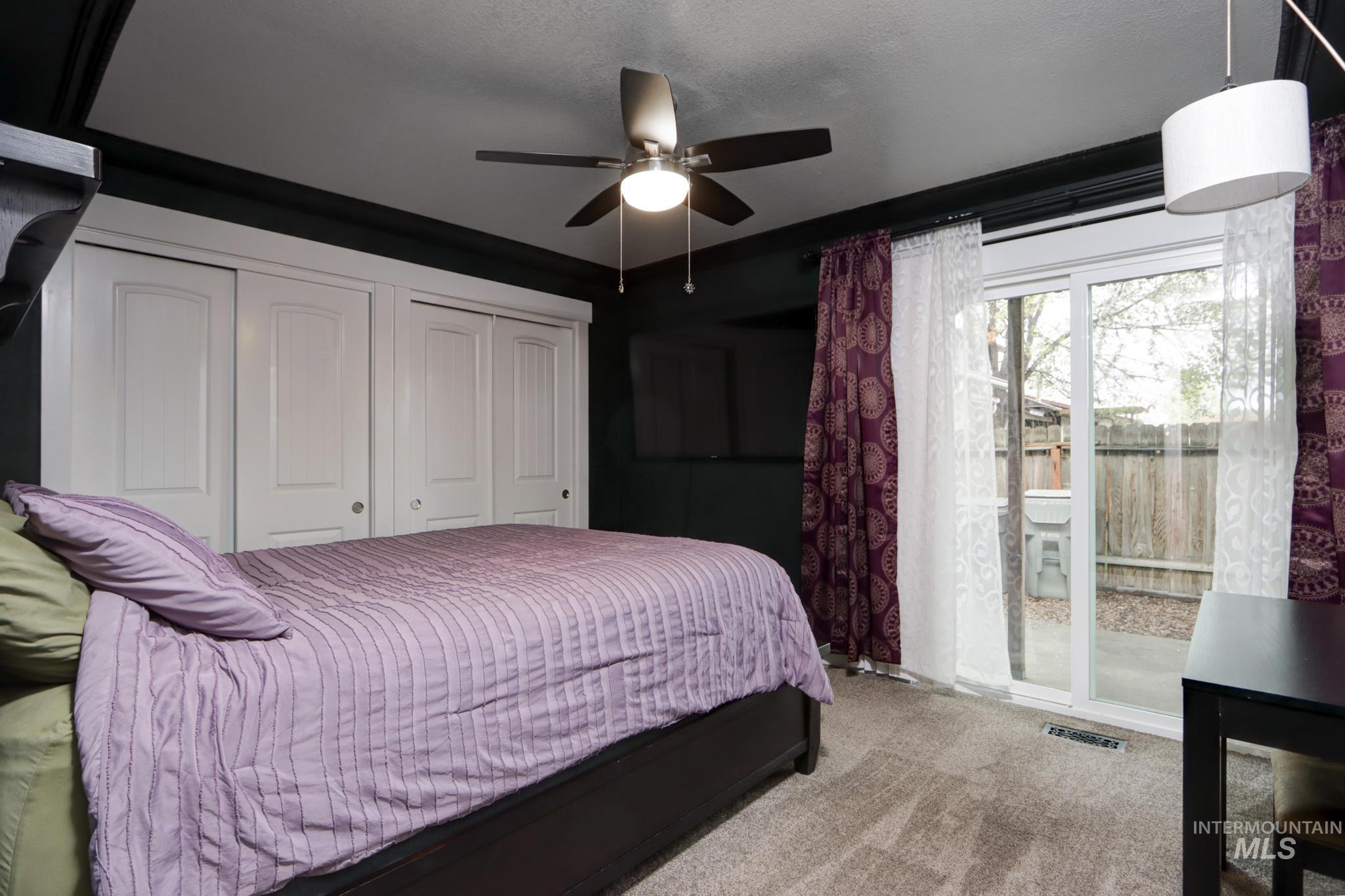 Bedroom featuring carpet flooring, a ceiling fan, two closets, and access to exterior