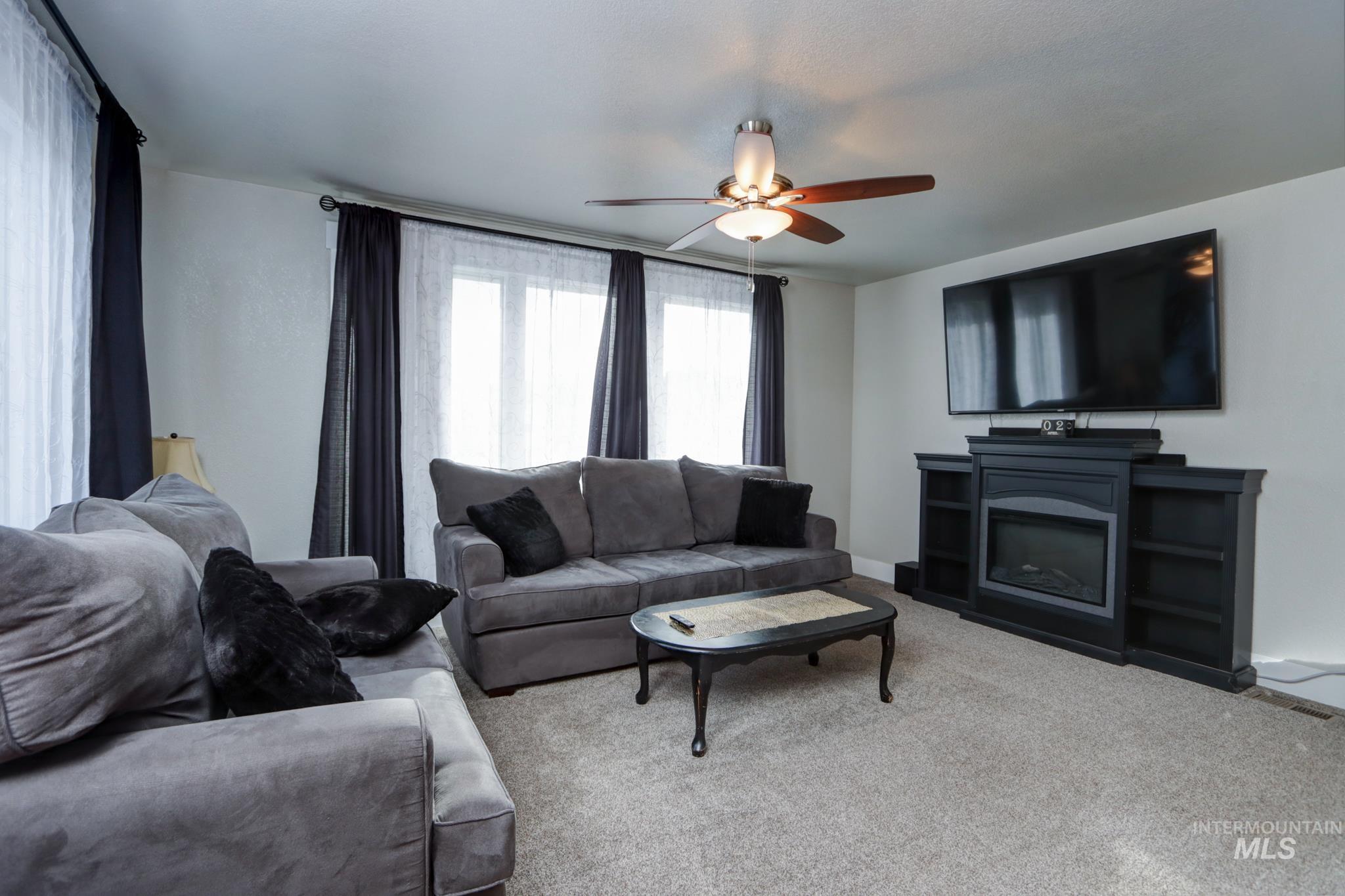 Carpeted living room with a ceiling fan