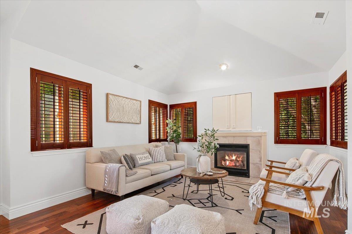 Living room with wood finished floors, healthy amount of natural light, a fireplace, and vaulted ceiling