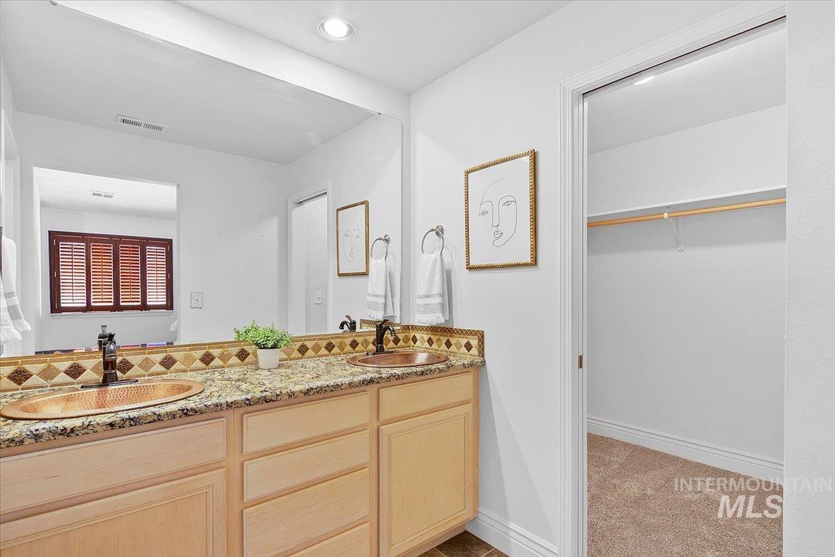 Primary bathroom with double vanity, a spacious closet, and recessed lighting