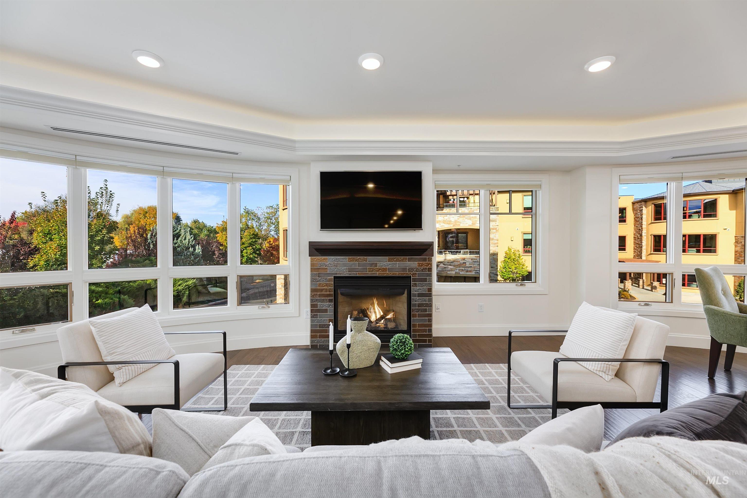 Wood floors, a brick fireplace, recessed lighting, and a tray ceiling