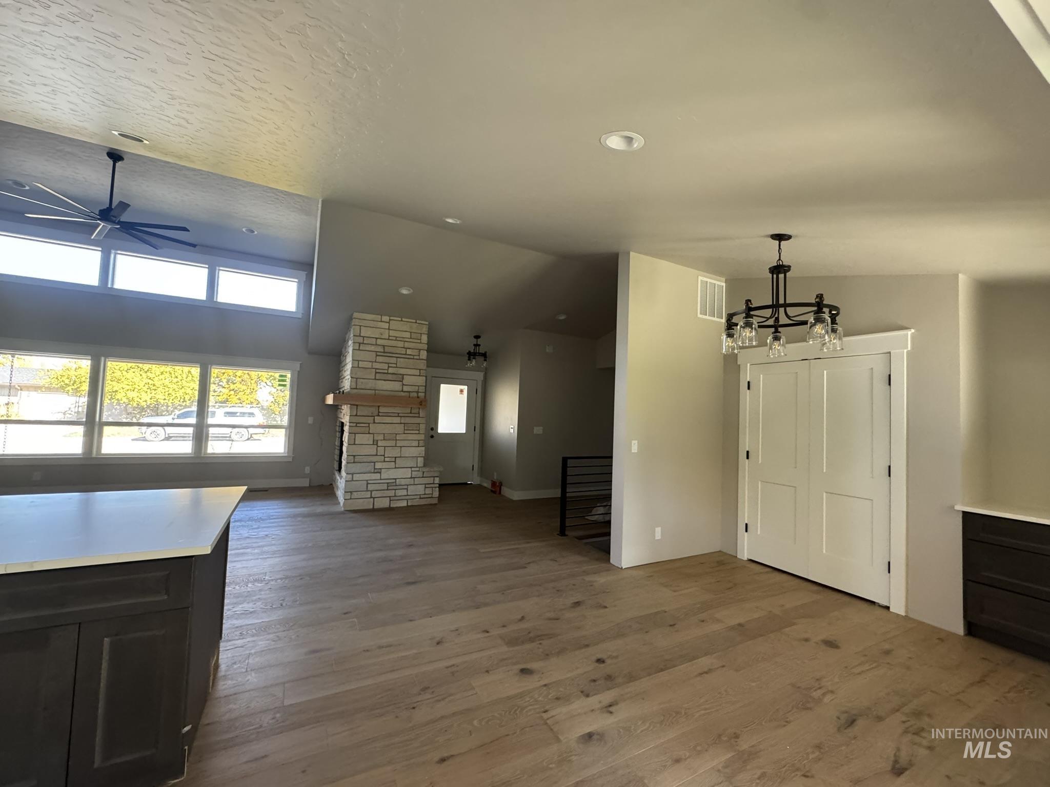 Unfurnished living room featuring light wood-style flooring, a ceiling fan, recessed lighting, lofted ceiling, and a textured ceiling